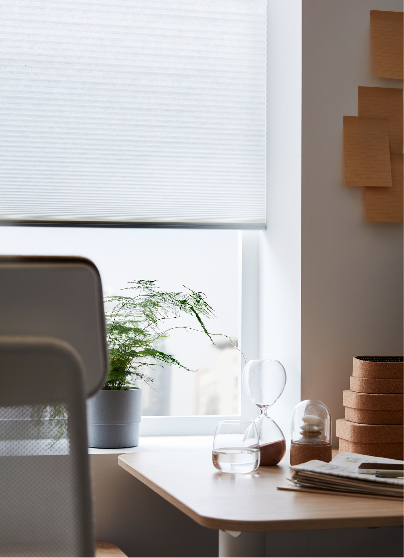 An IKEA HOPPVALS cellular blind, with a honeycomb structure, at a window, behind a work desk and chair.