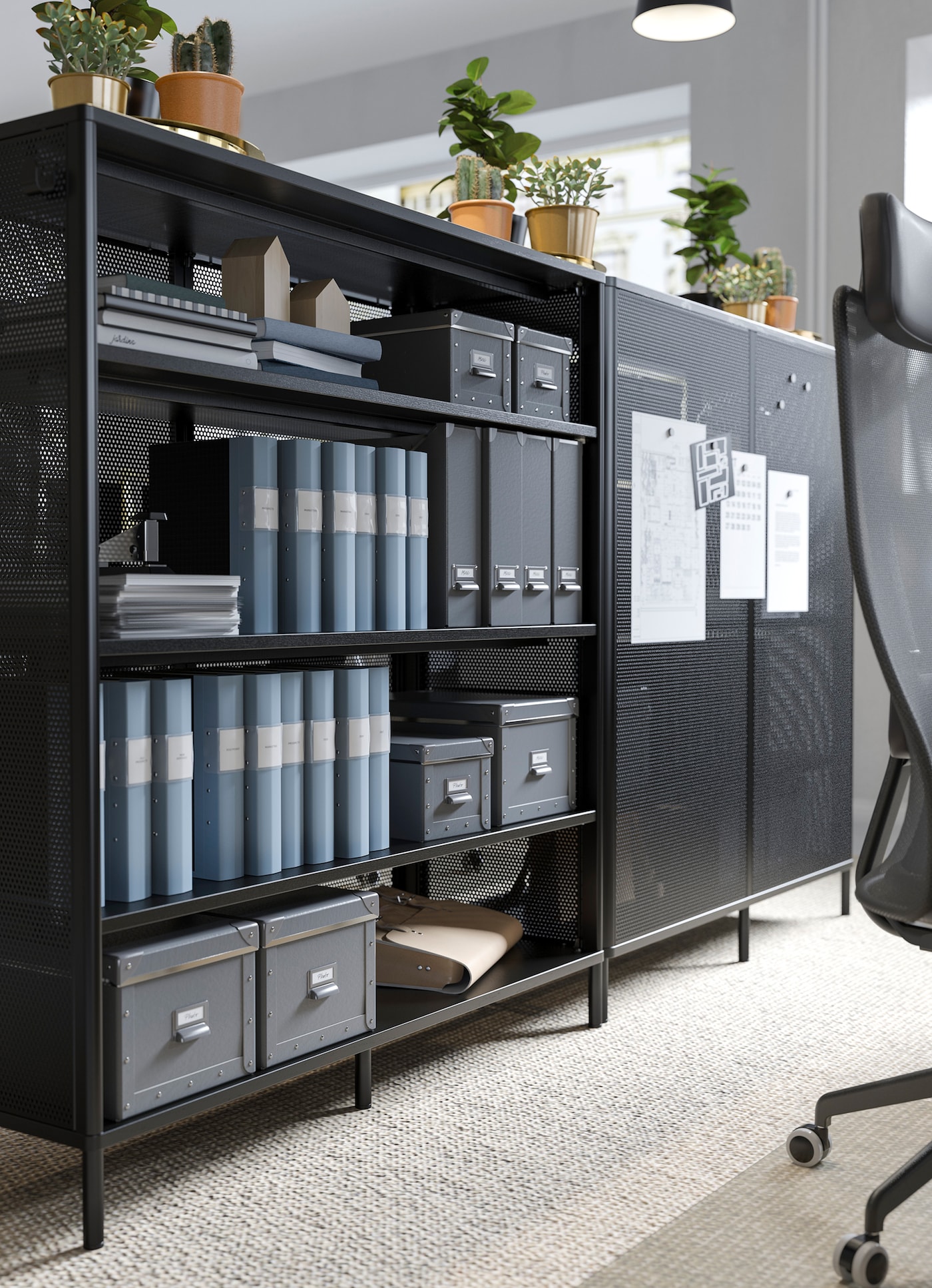 IKEA BEKANT black office shelving unit used as a divider, with paper reminders attached to its magnetic mesh door.