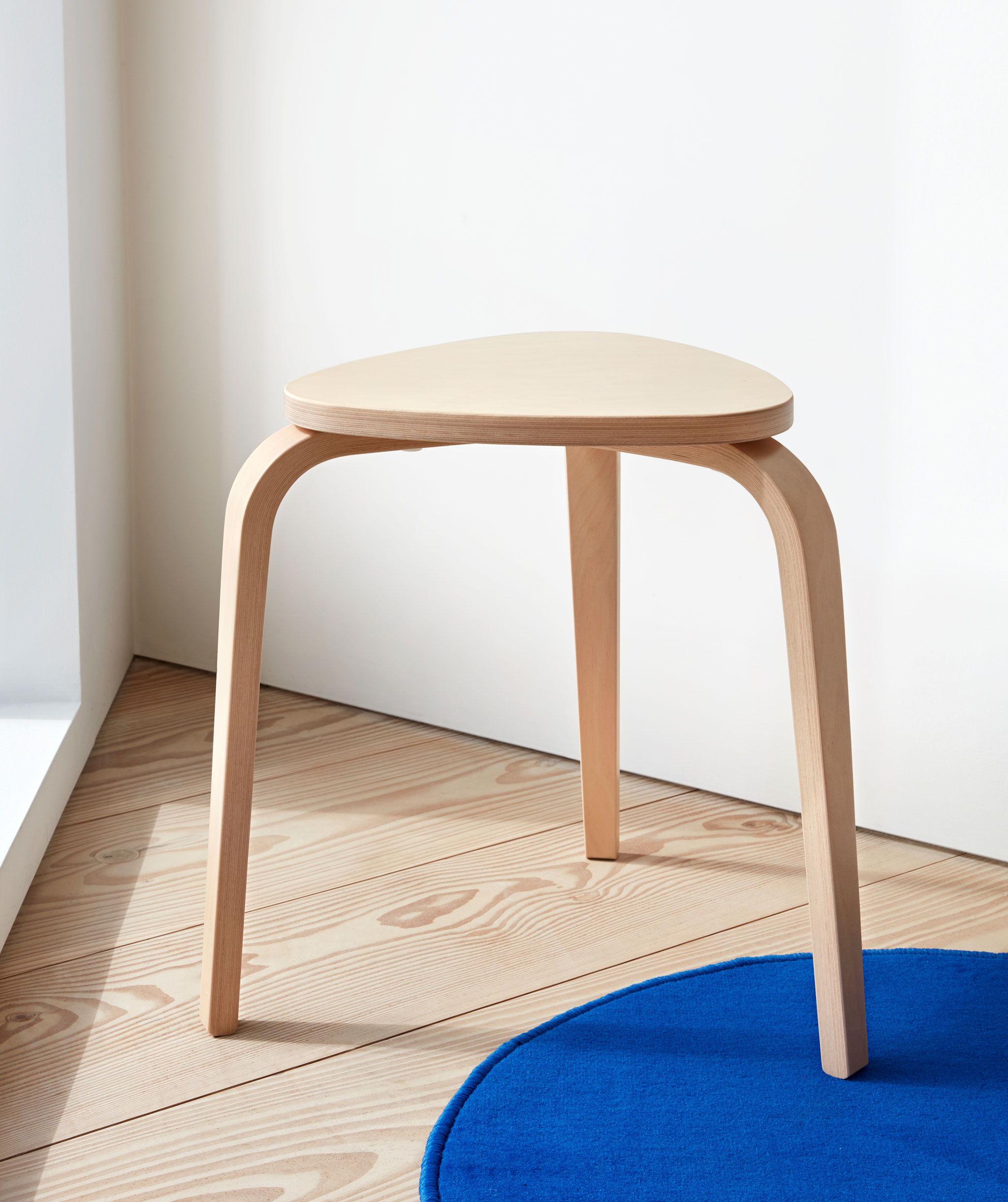 three-legged, light-wood stool standing in a sh