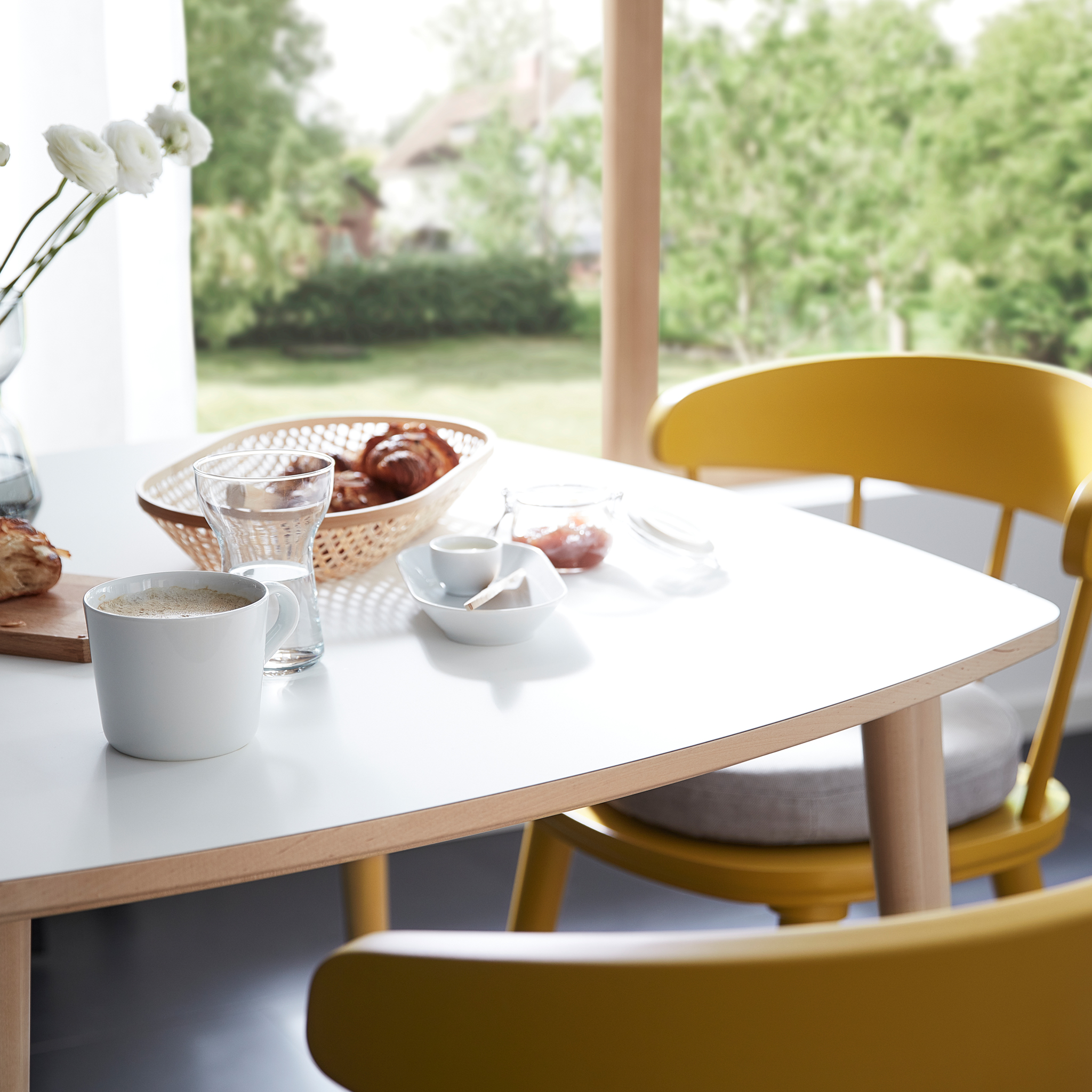The OMTÄNKSAM table, scratch resistant and easy to clean, is set for breakfast and accompanied by two OMTÄNKSAM chairs.