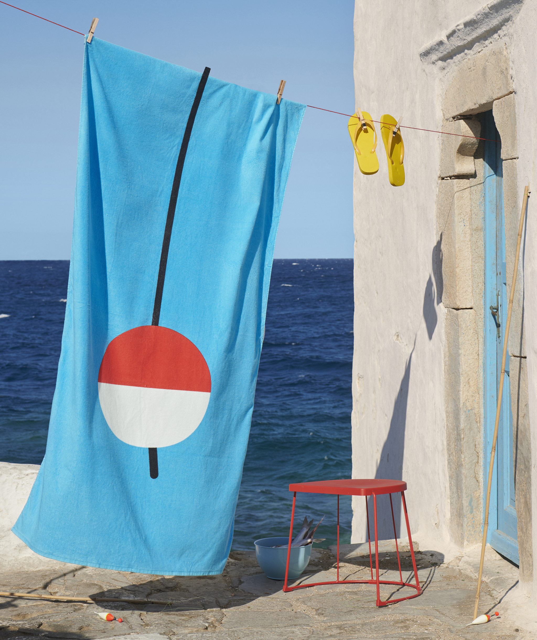 a brightly coloured beach towel and flip flops hanging from a