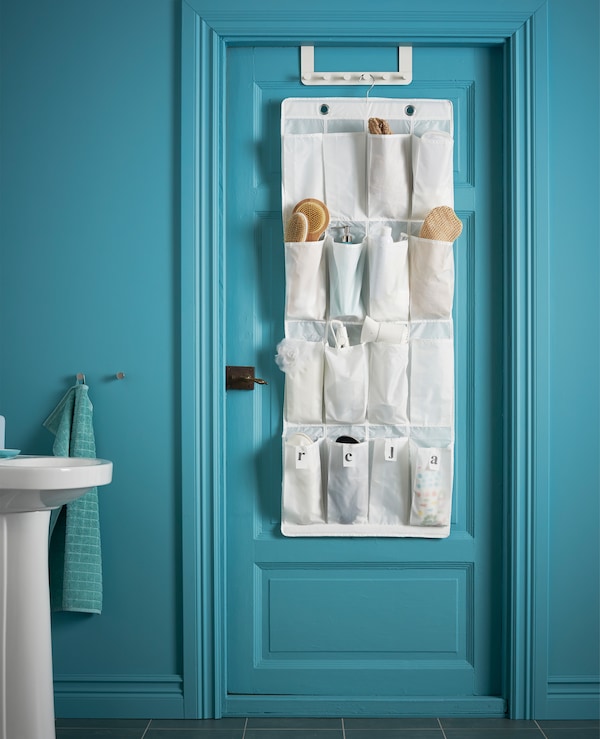 A bathroom door with hanging shoe organiser whose pockets hold brushes, hair sprays and other toiletries.