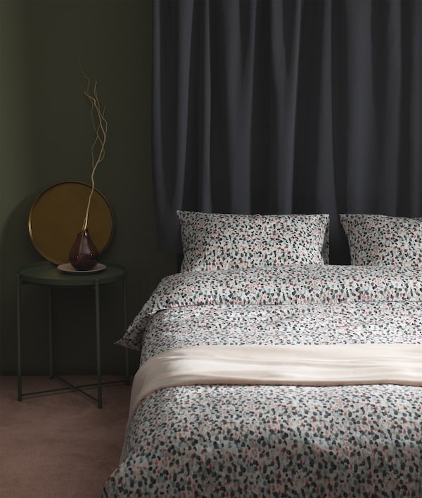 A bed with quilt cover and two pillowcases made of 100% cotton, with a dotted pattern in blue, grey, beige and apricot, that looks like strokes of watercolours.