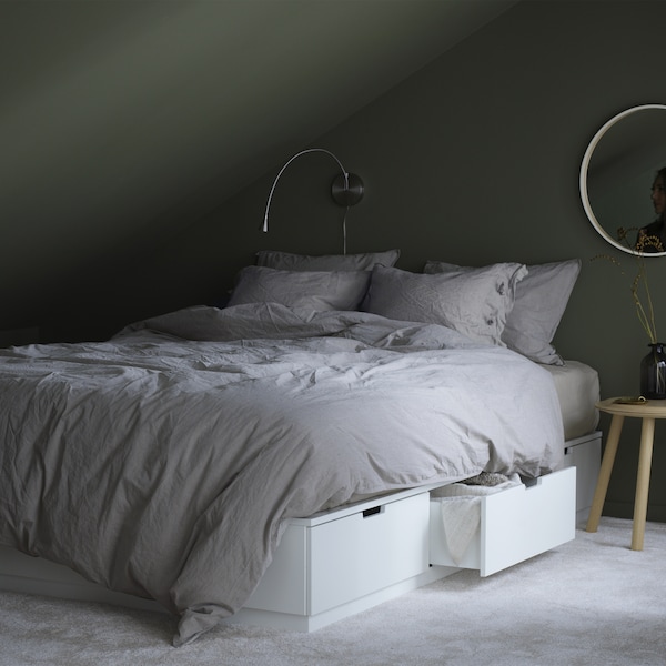 A bedroom with a white bed that includes six soft-closing drawers for extra cushions and blankets, three on each side.