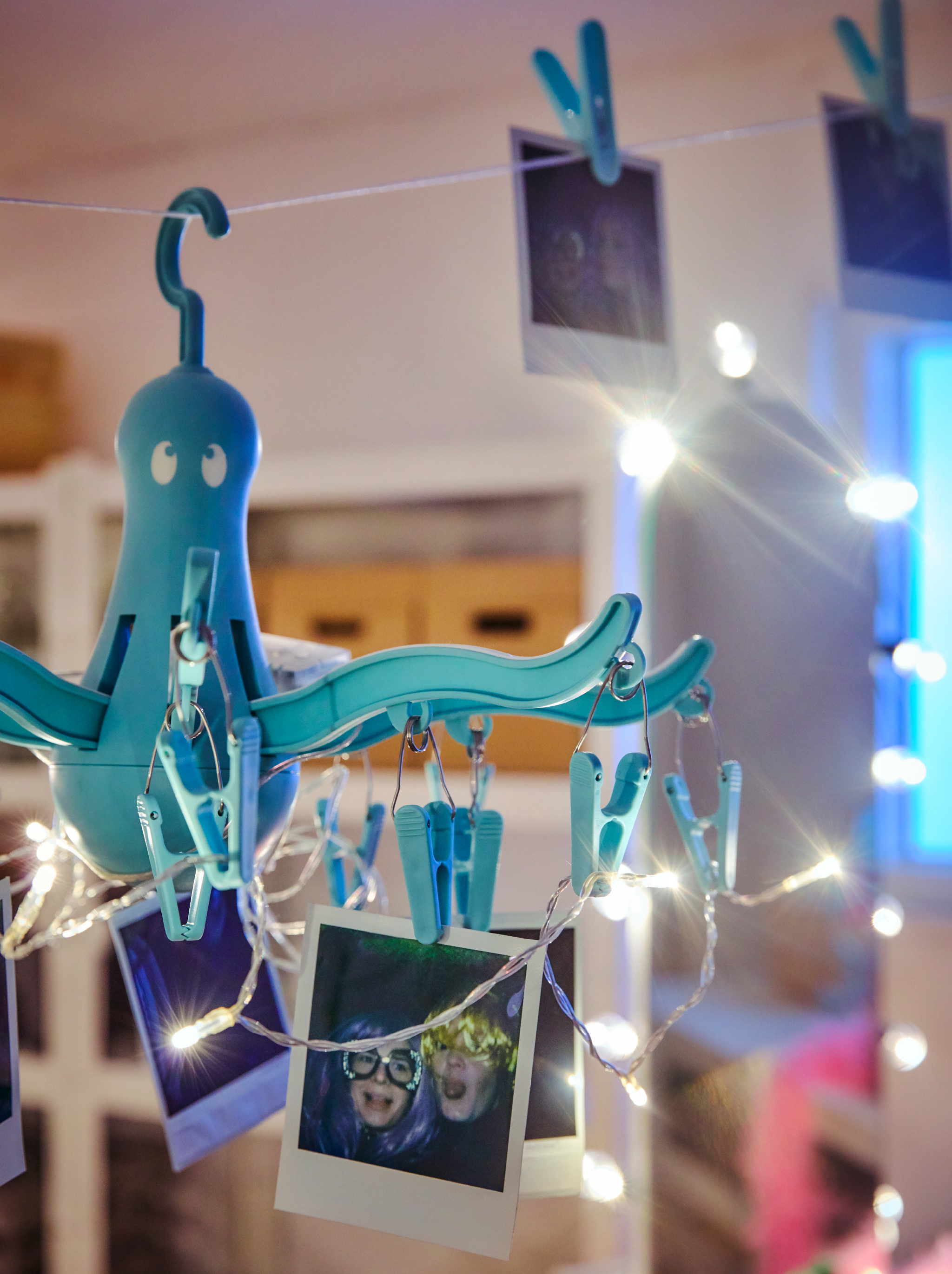 A chandelier made from a PRESSA hang dryer and a LEDFYR lighting chain, with Polaroid snaps hanging from the clothes pegs.