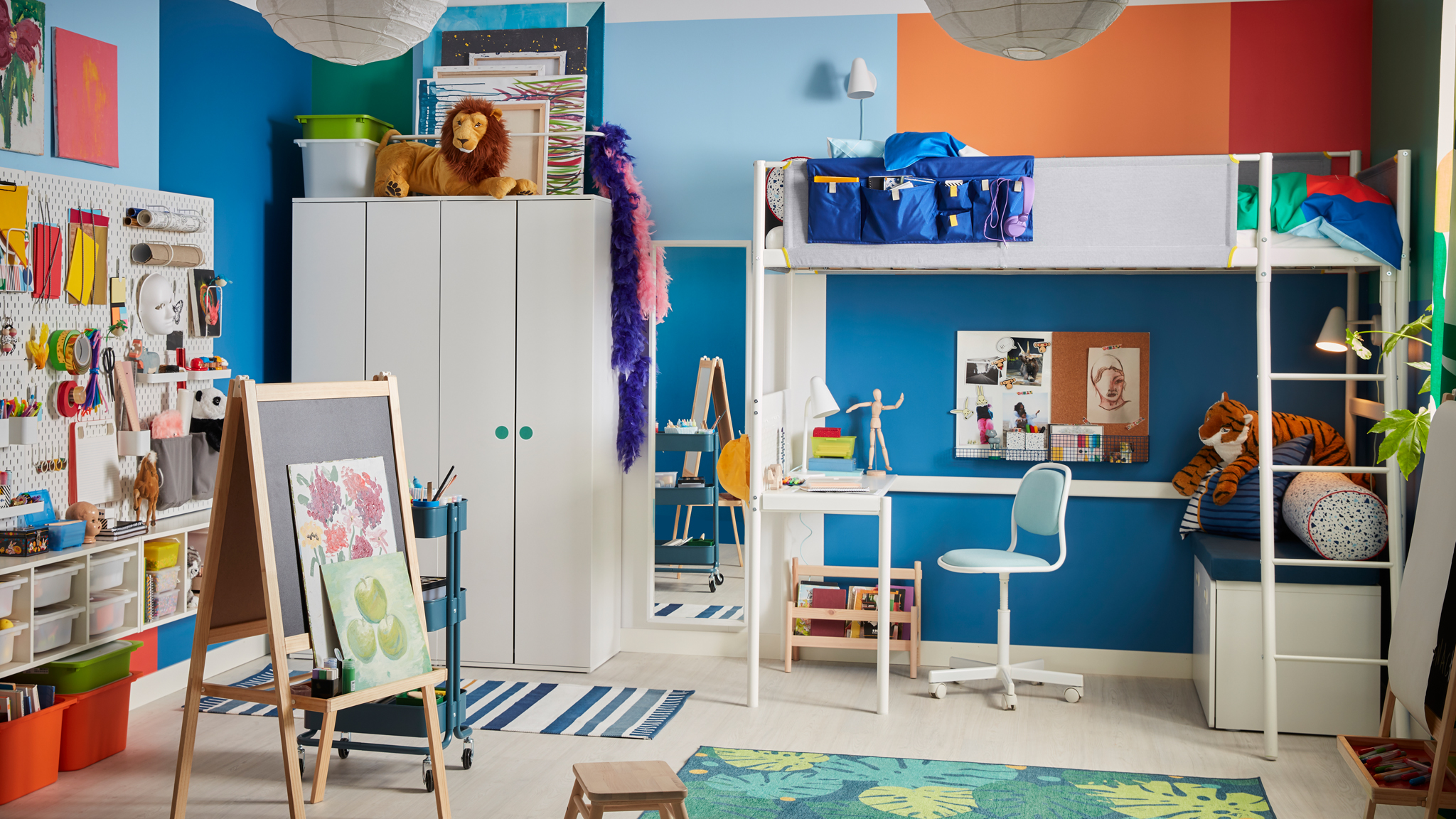 A children’s room with a white VITVAL loft bed with a built-in desk underneath, a MÅLA easel and lots of different storage.