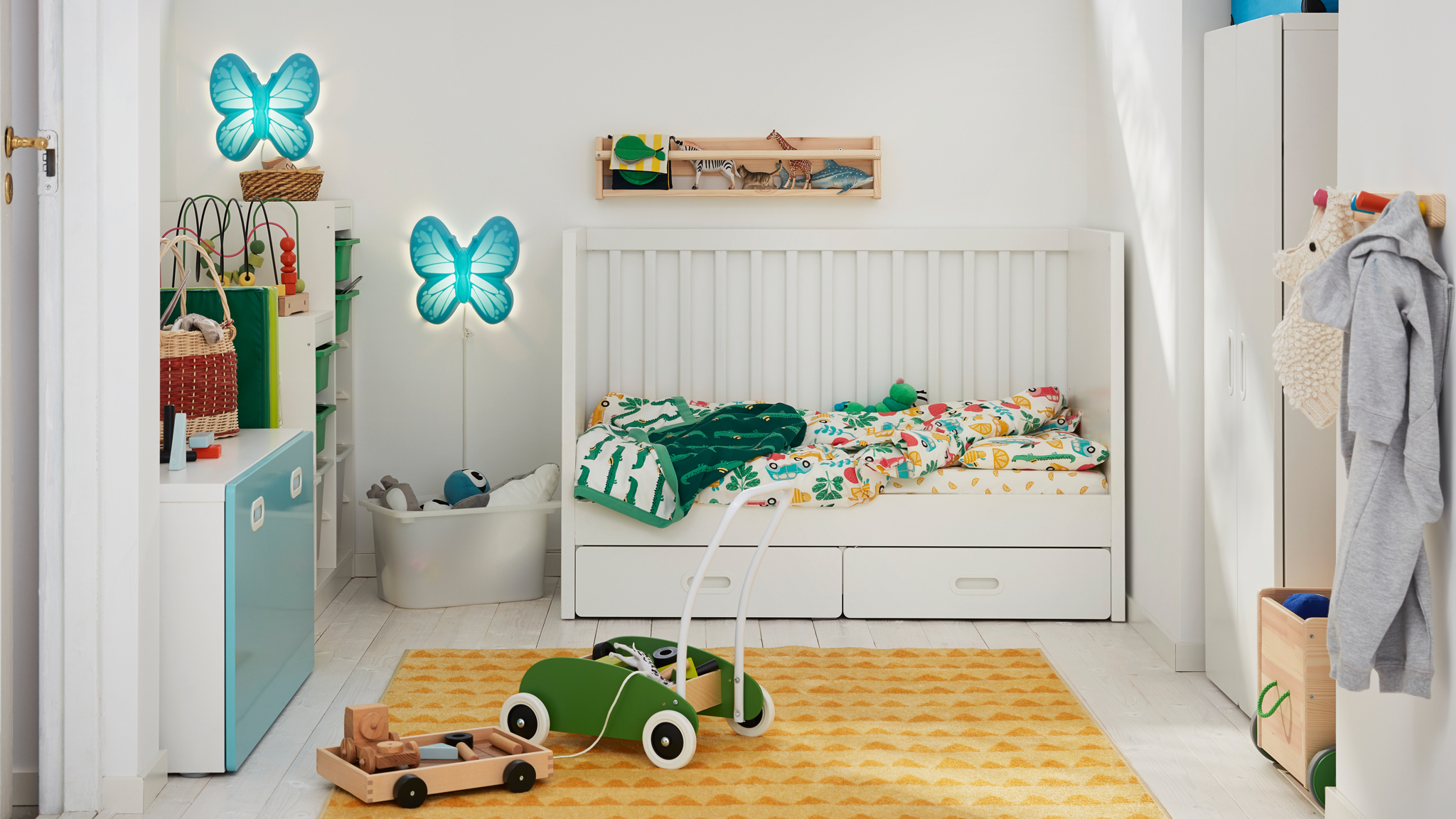 A child’s bedroom with a STUVA/FRITIDS cot with one side removed and a green MULA toddle truck on a RÖRANDE rug.