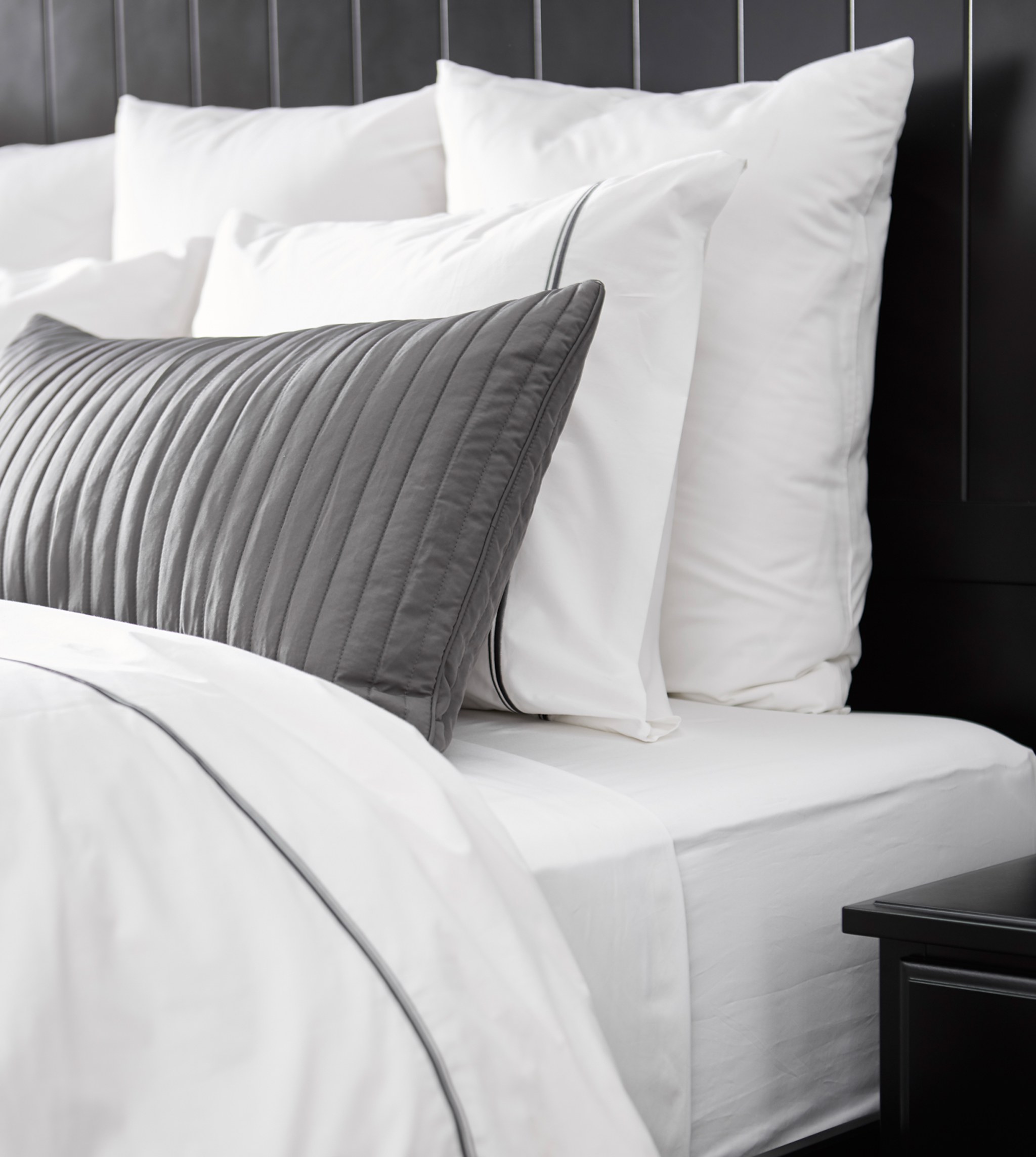 A close-up image of a bed made up with lots of fluffy pillows.