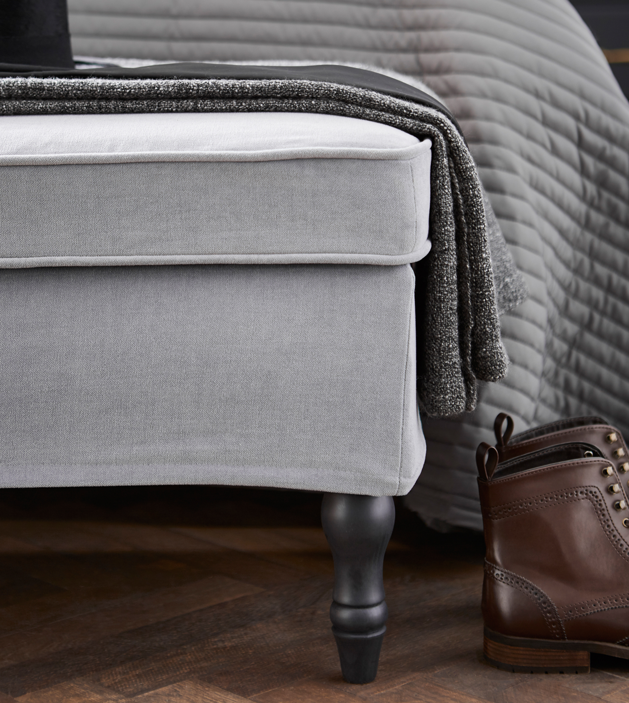 A close-up image of a bench and a throw at the foot of a bed.