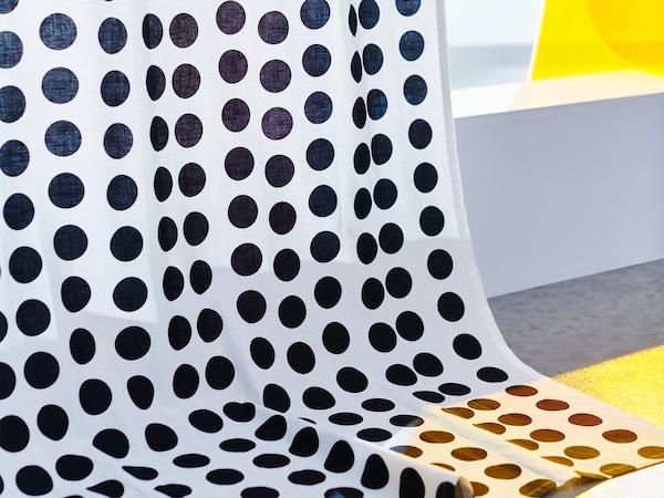 A close-up of KLARASTINA curtains with a pattern of black polka dots on a white background.