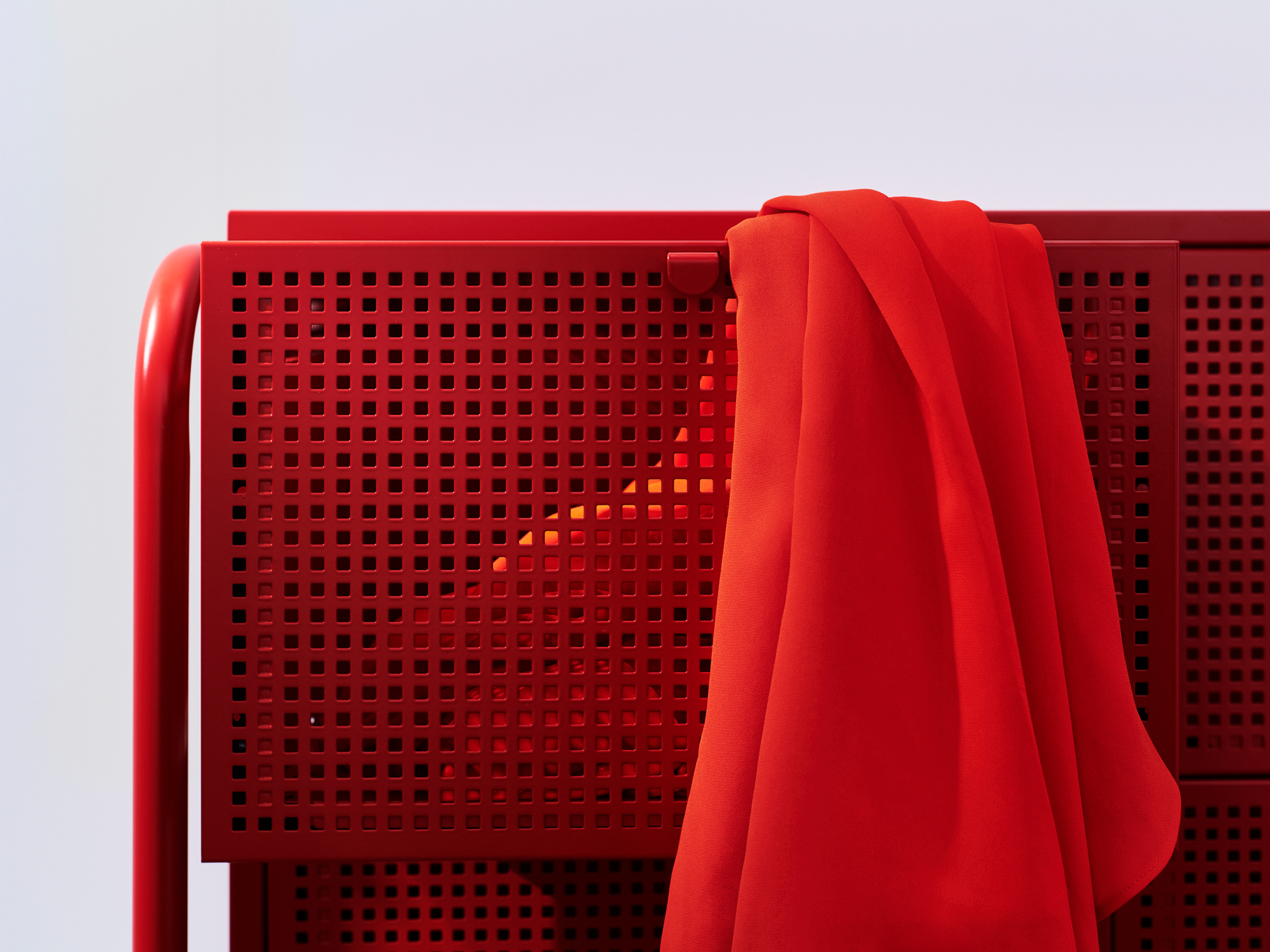 A close-up of the industrial-styled red NIKKEBY chest of drawers in perforated metal.