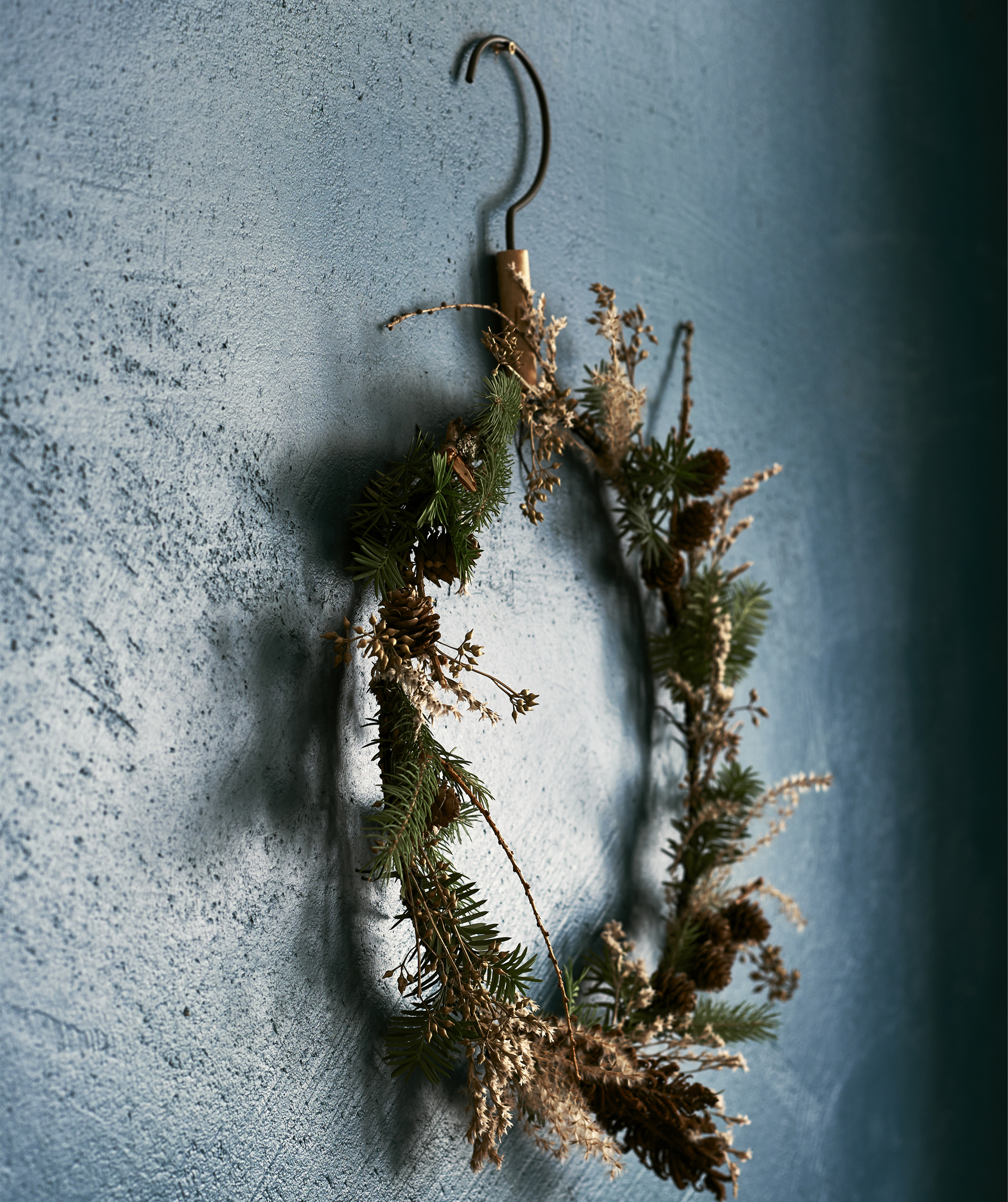 A floral wreath hanging on a blue wall.