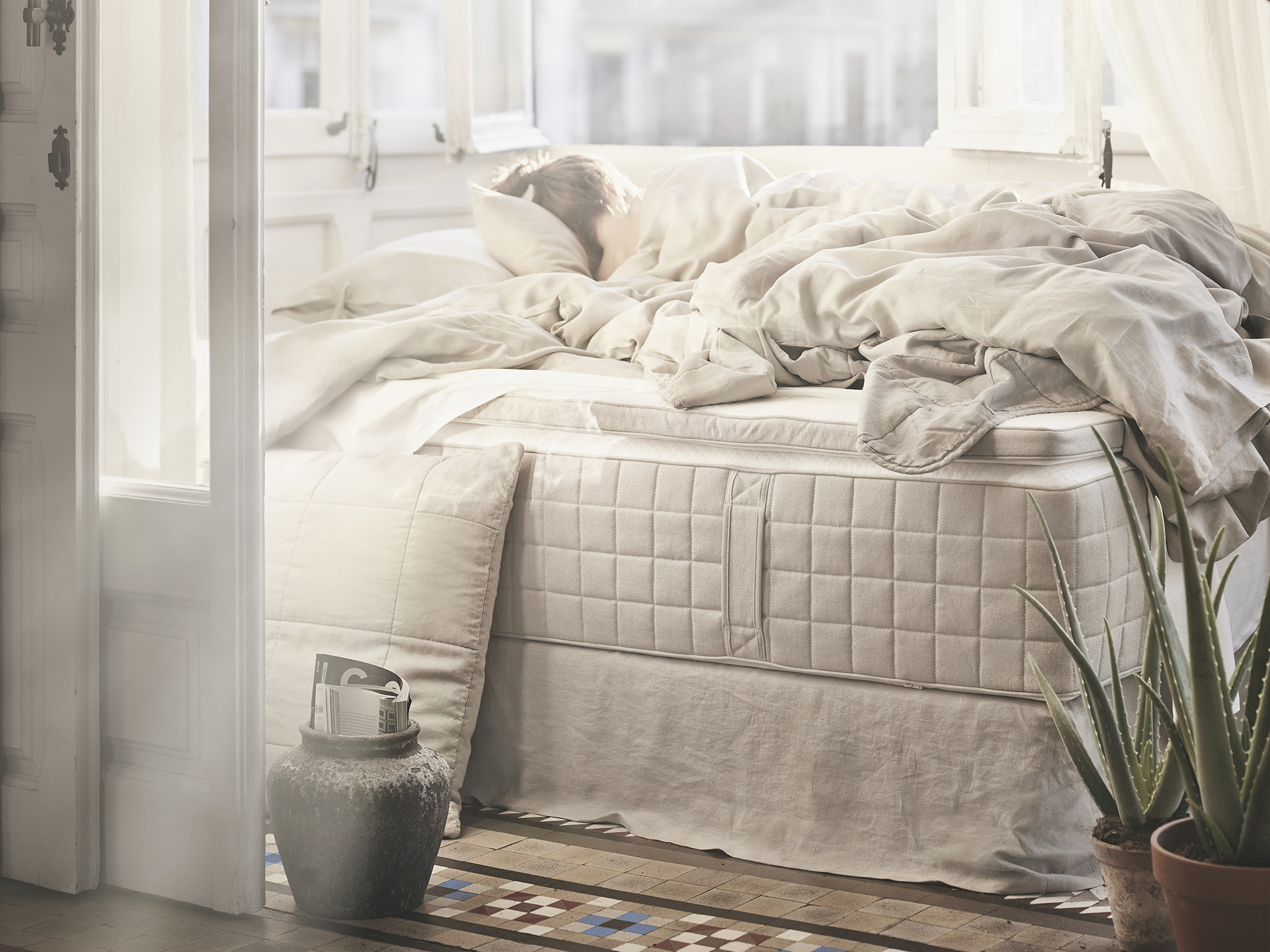 A HIDRASUND pocket sprung bed mattress with white/natural bedding and pillows thrown on it.