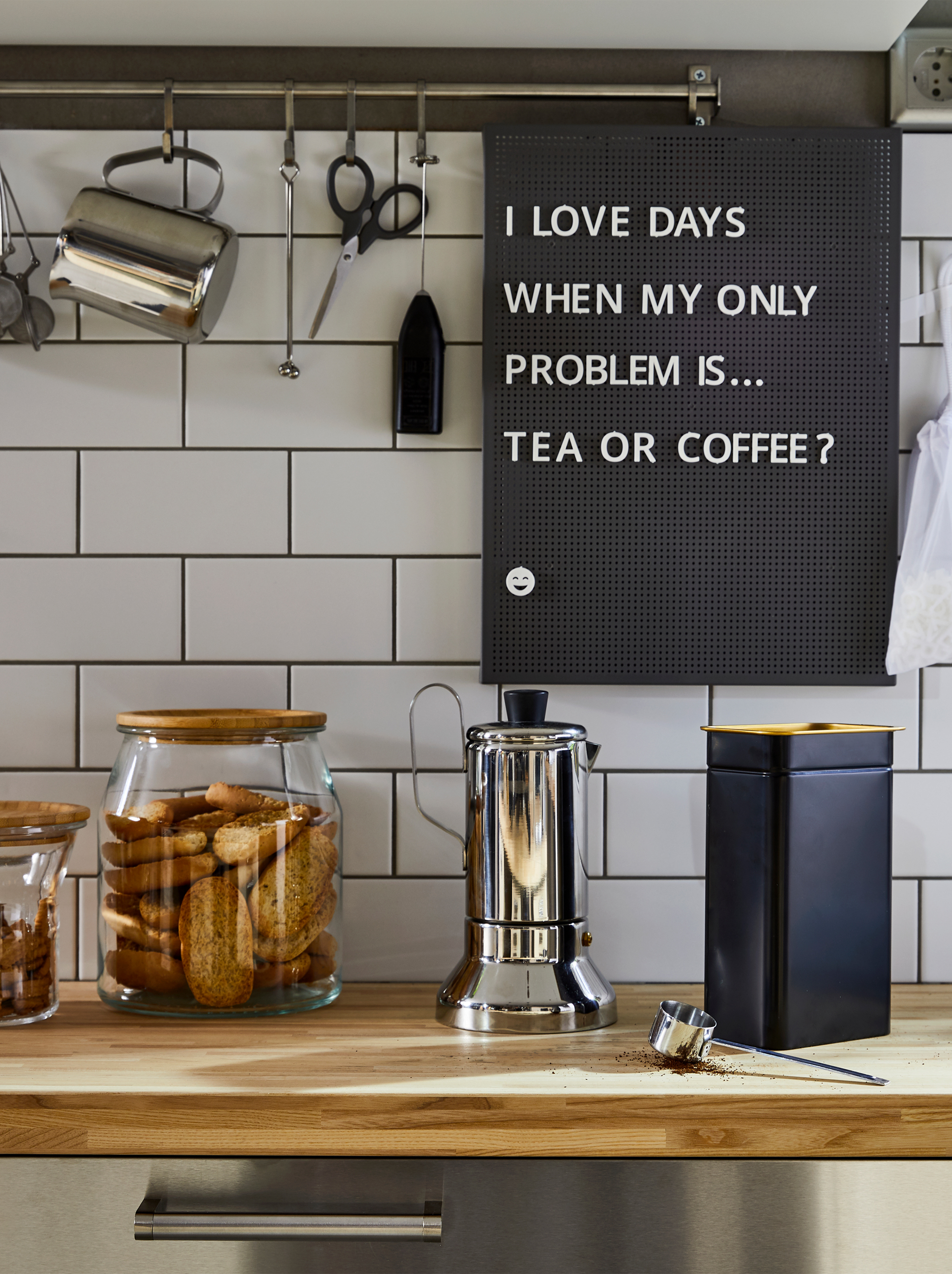A kitchen worktop with a METALLISK espresso maker in stainless steel, a blue BLOMNING coffee tin and glass jars for cookies.