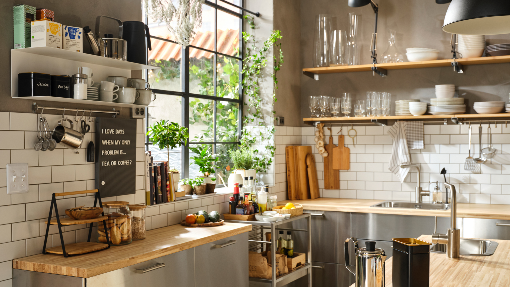 A large, semi-professional kitchen with wooden work tops, stainless steel fronts and open shelves for dinnerware.
