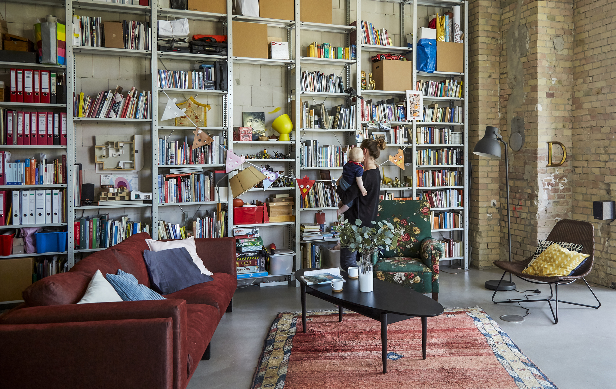 A living room with a red sofa and wall of shelves.