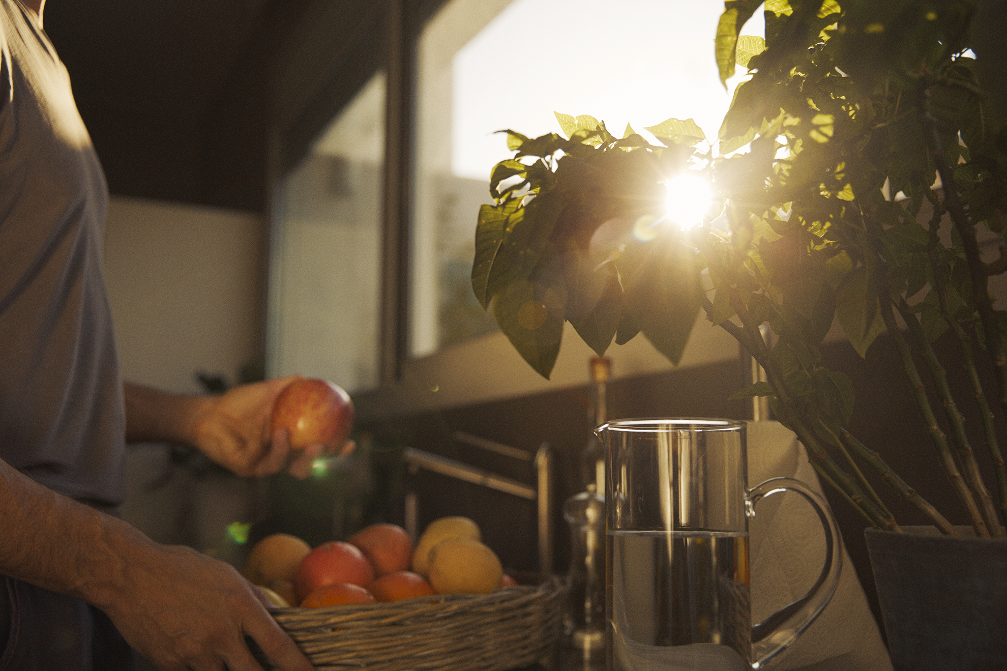 A man fetches fruit on a balcony as the sun sets.