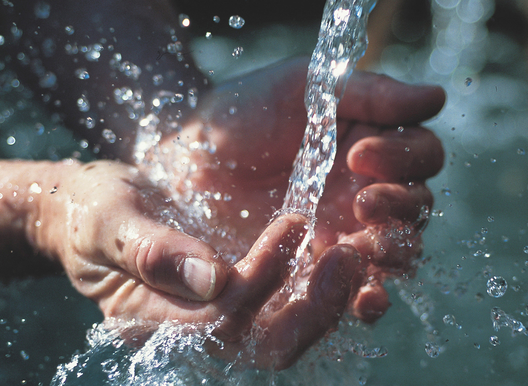 A pair of hands cupping water from a tap.