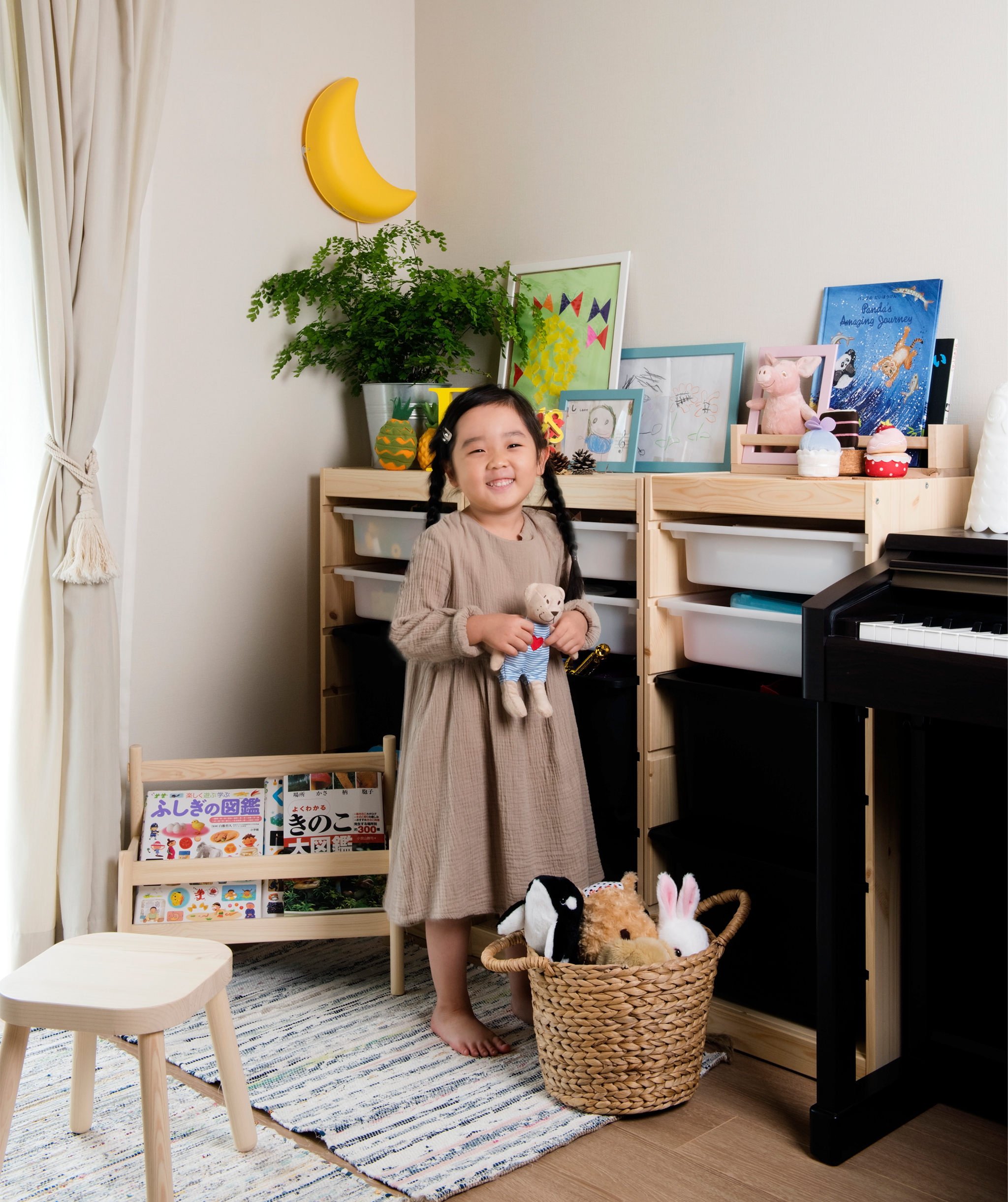 A portrait of Mieko’s daughter standing next to her toy storage unit in the living room.