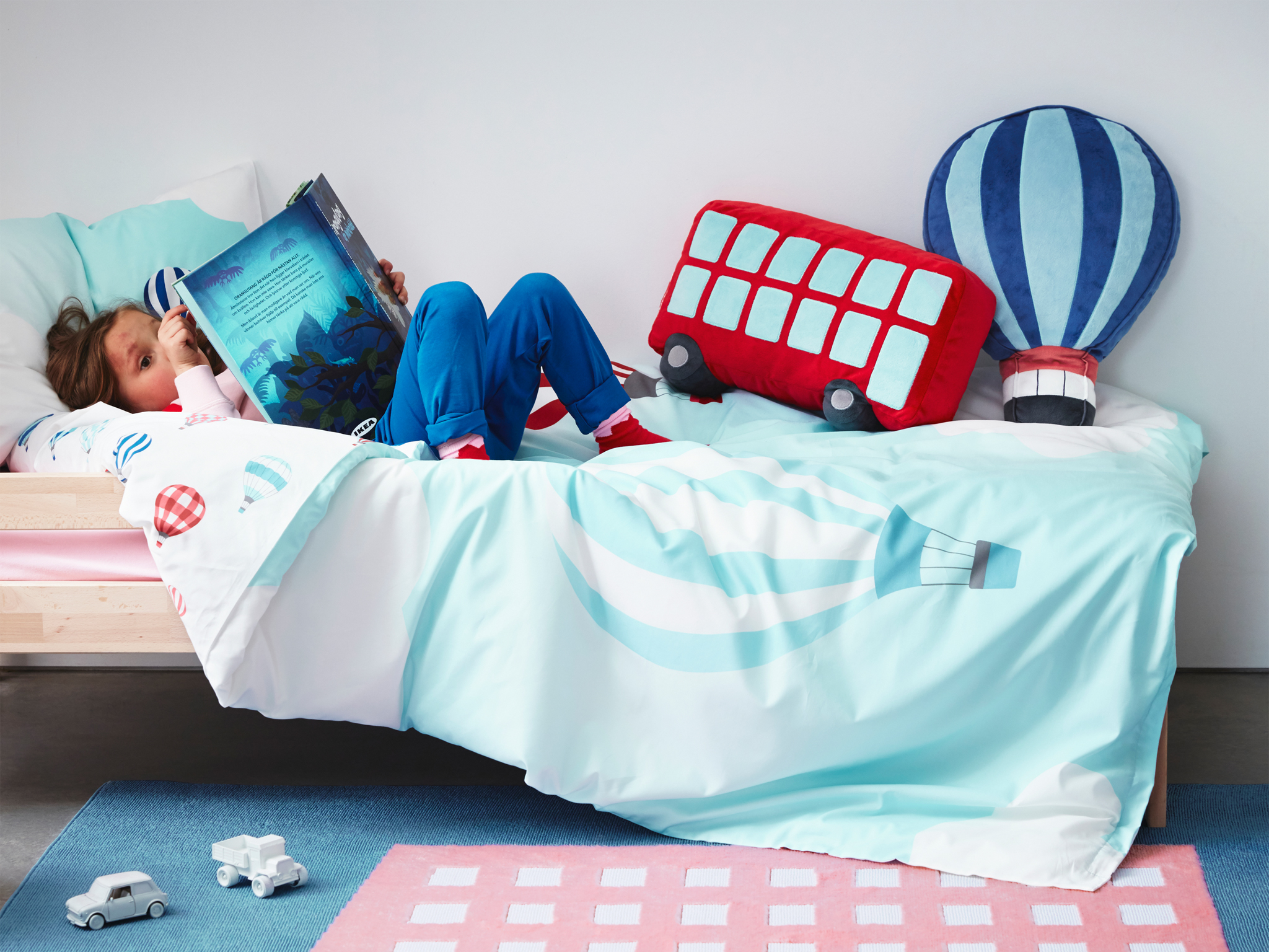 A quilt cover, rug and cushions from UPPTÅG children’s textile collection with colourful graphics based on travelling.