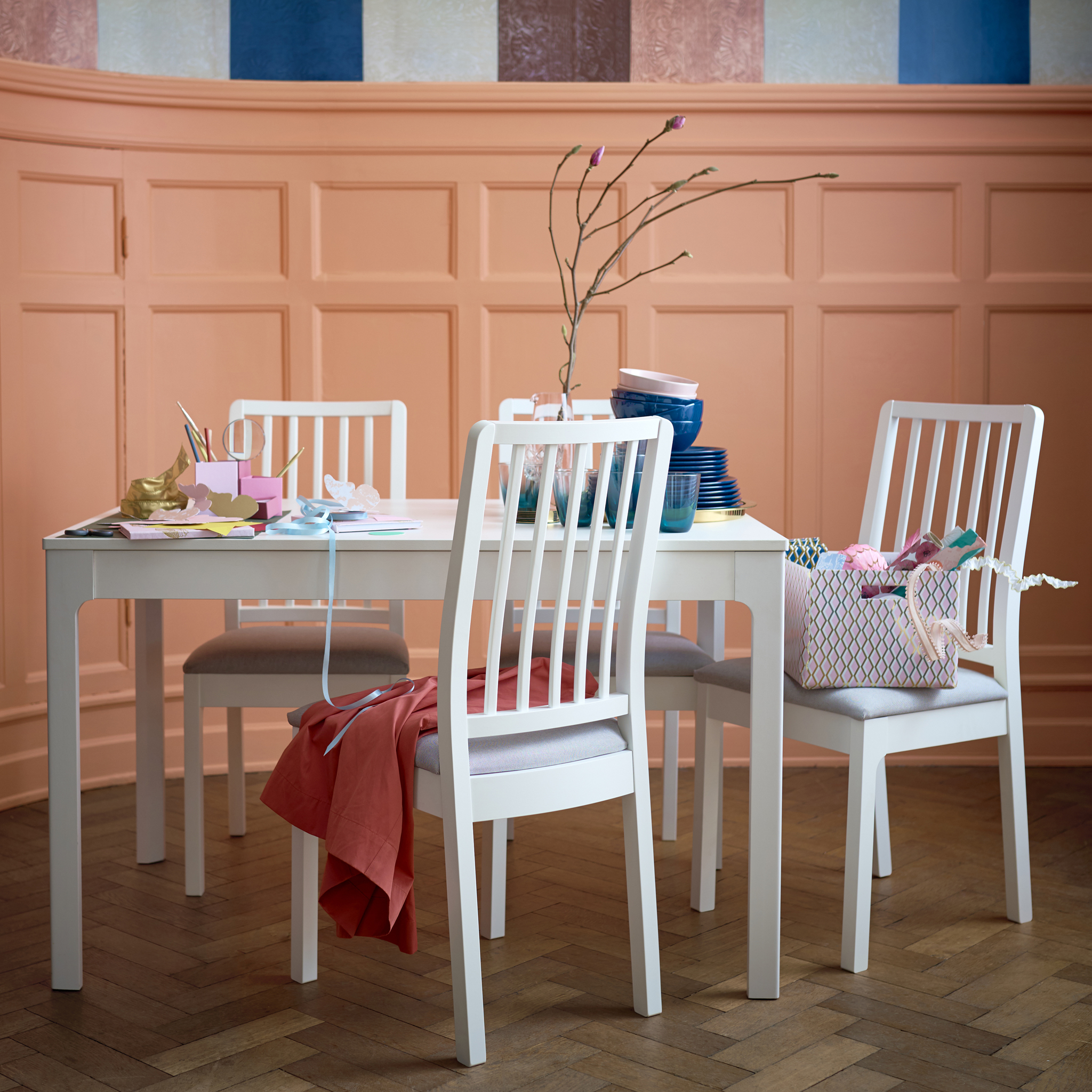 A short white dining table with white chairs.
