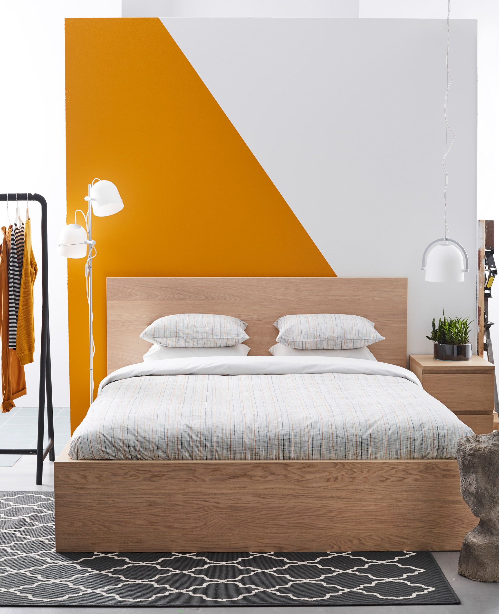 A simple, clean bedroom with a graphic orange and white wall.