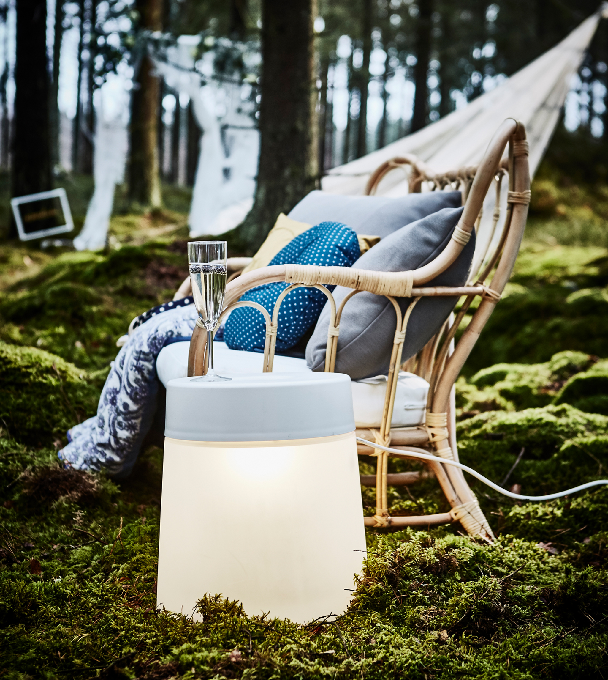 A stool lamp being used as side table for an armchair in a forest wedding lounge