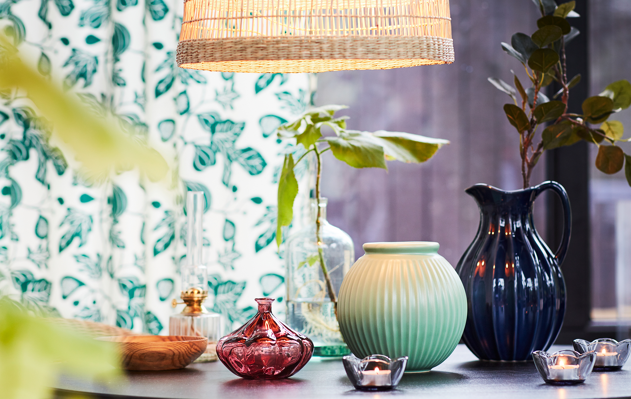 A table lightly decorated with small vases and candles with little green leaves and signs of spring.