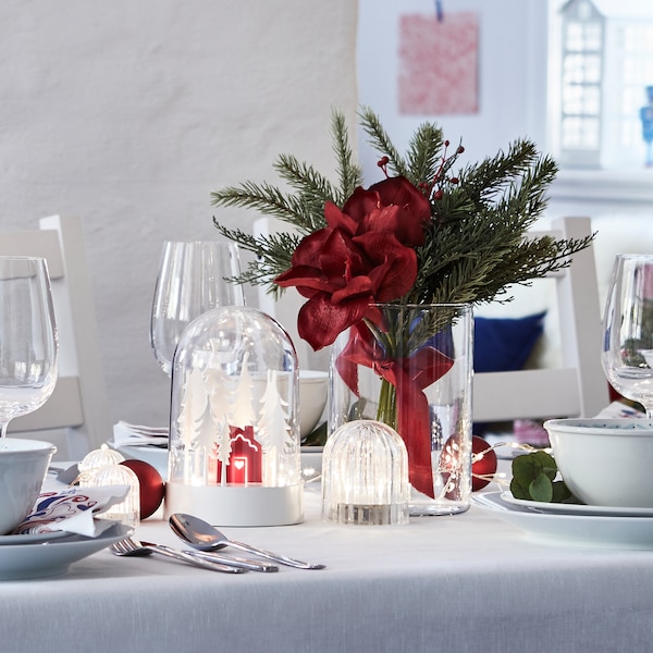 A table prepared for the festive winter season with STRÅLA LED table decoration, VINTERFEST tableware and artificial bouquet.