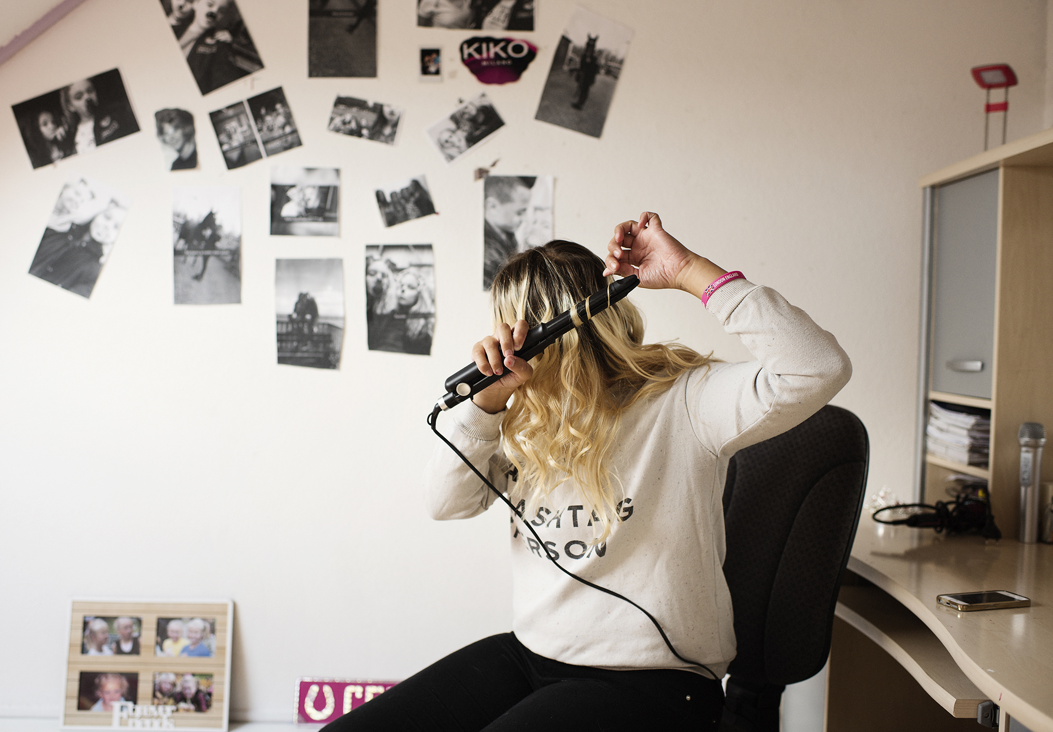 A woman curling her hair with an electrical curler.