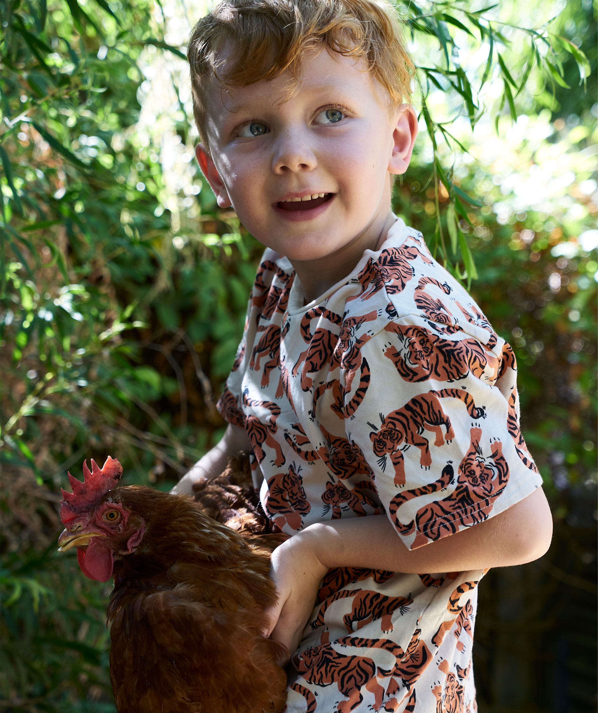 A young child holds a chicken.