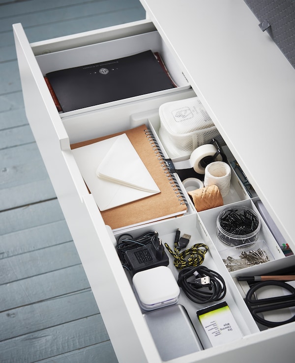 An aerial view of a drawer and an insert with compartments for organised scissors, tape, cords, tape, etc.