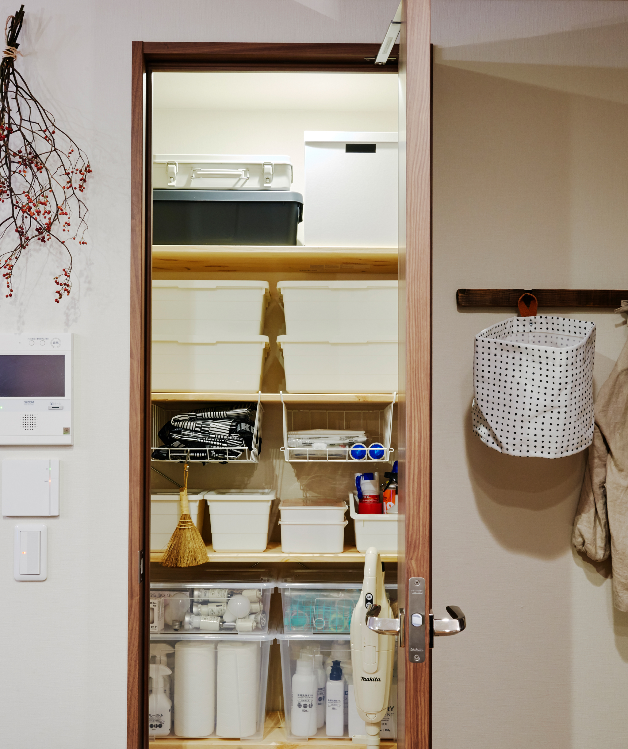 An open cupboard with white storage boxes stacked on shelves inside.