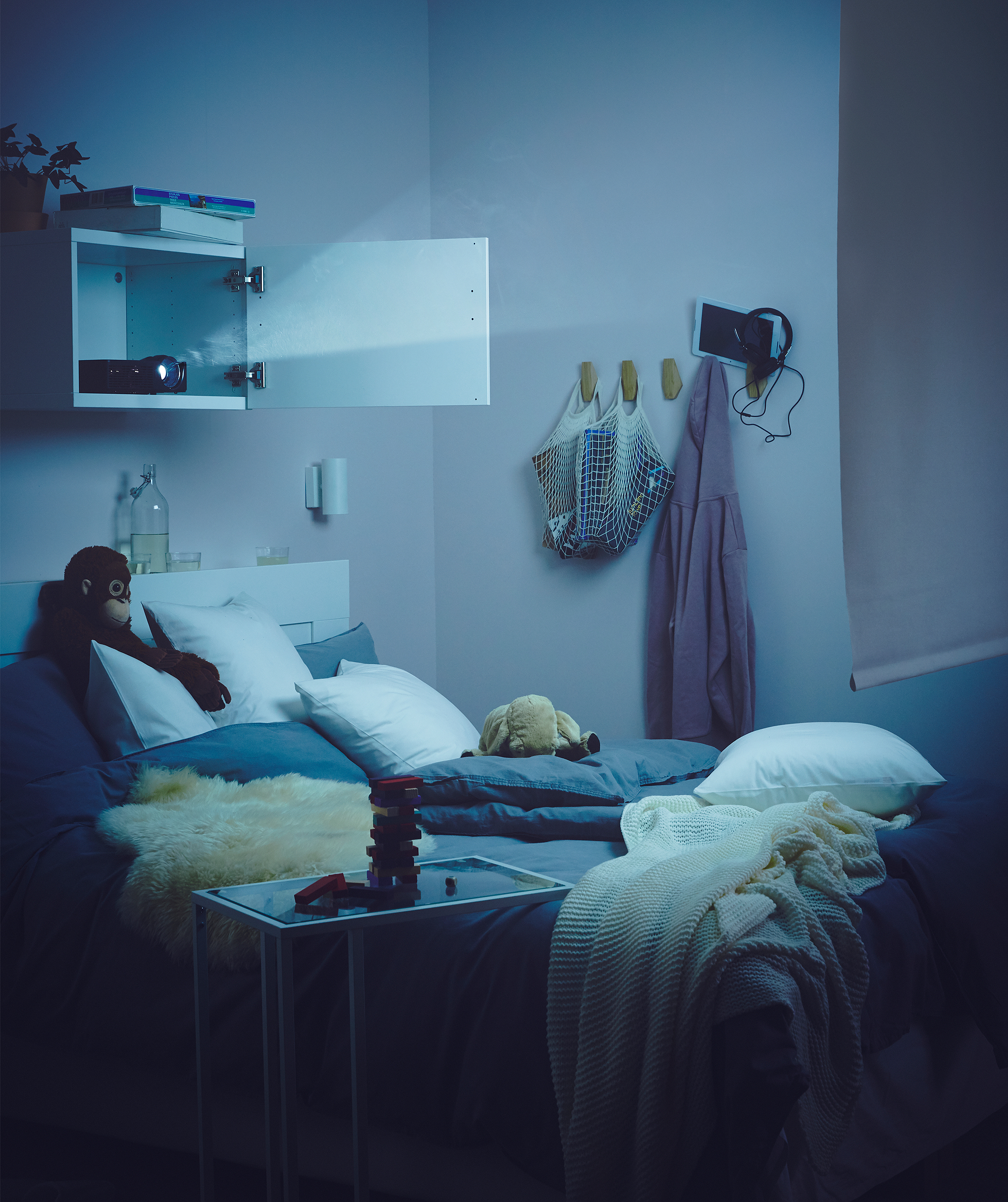 昏暗的卧室里,床上方壁橱内摆放着投影仪,光线照向房间另一头的卷帘.