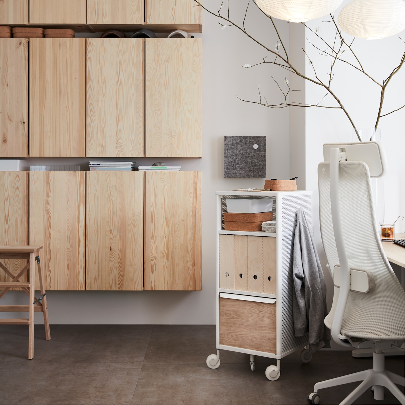 IKEA IVAR pine wall cabinets, a white mesh storage unit on castors and a swivel chair, in an office space.