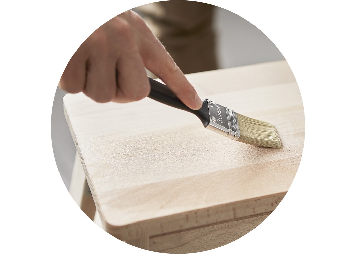 Close-up of a hand with a paintbrush painting a stool.