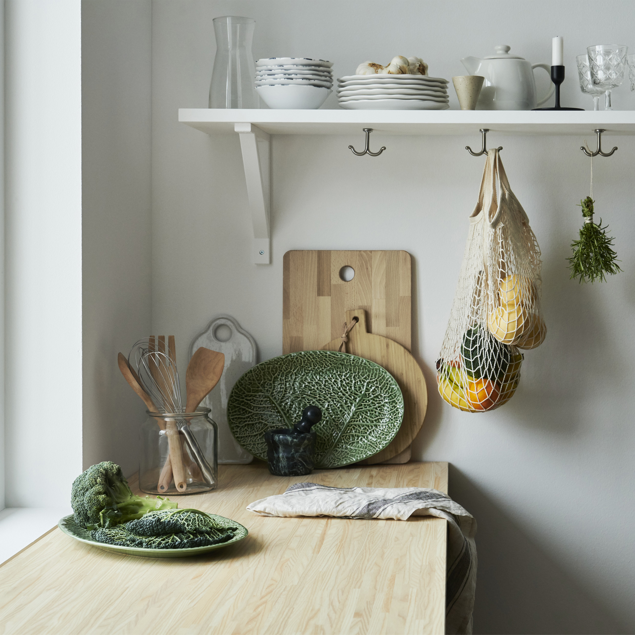 木质厨房操作台面上摆放着叶片造型的盘子,搁板上摆放着木质砧板和