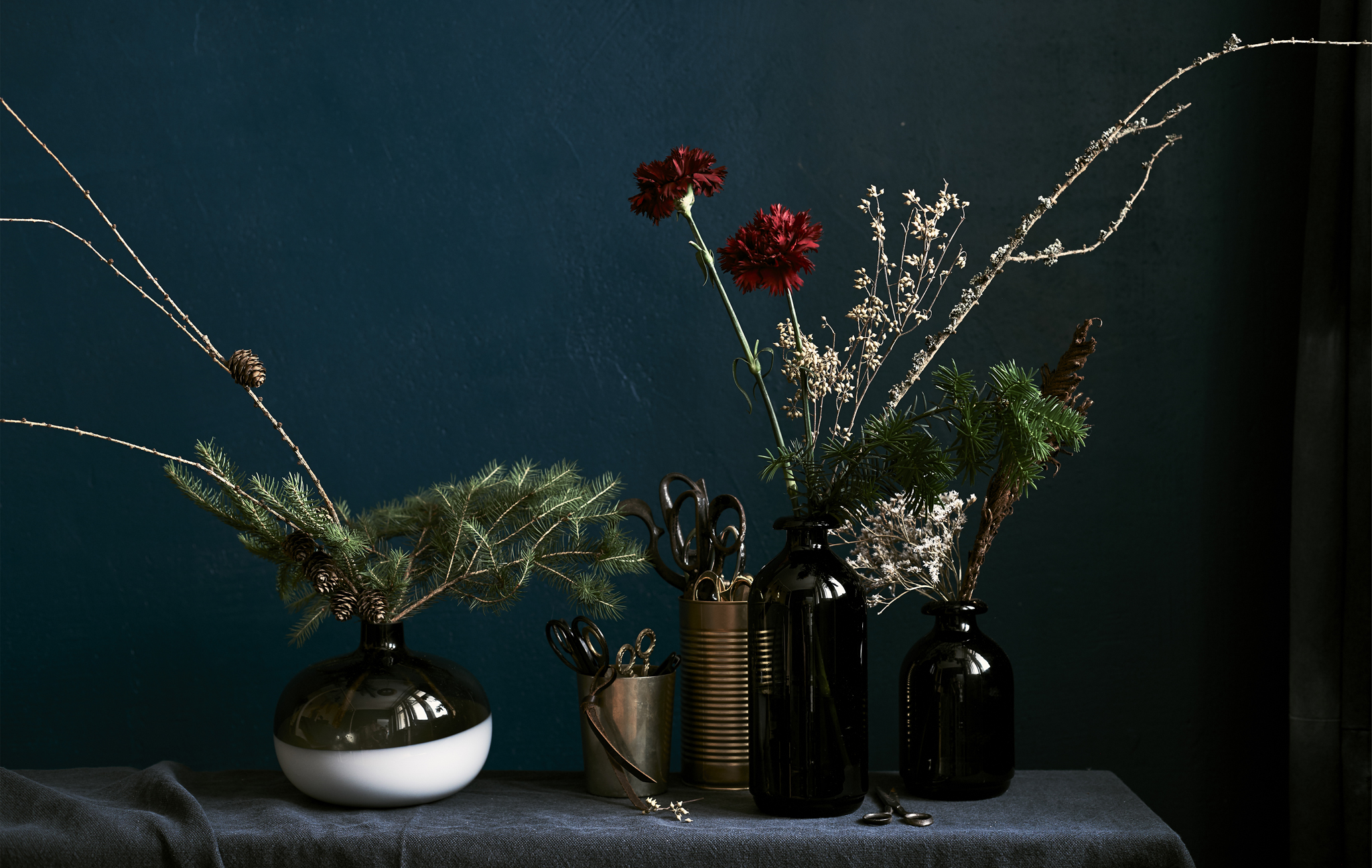 Floral displays in different size vases against a dark backcloth.
