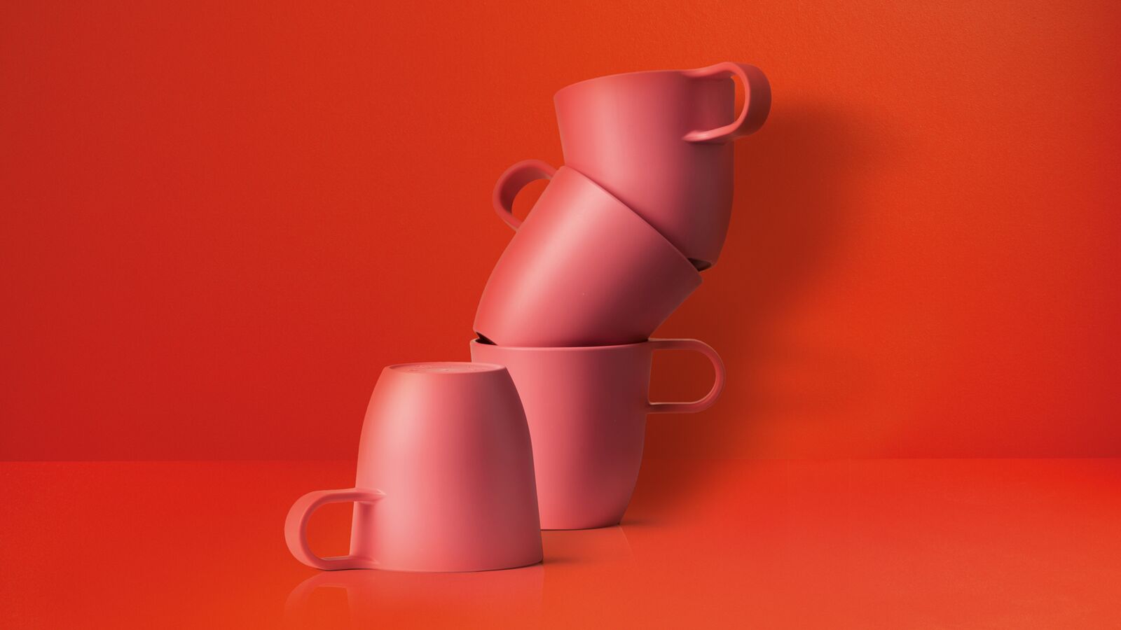 Four red mugs over red background, stacked