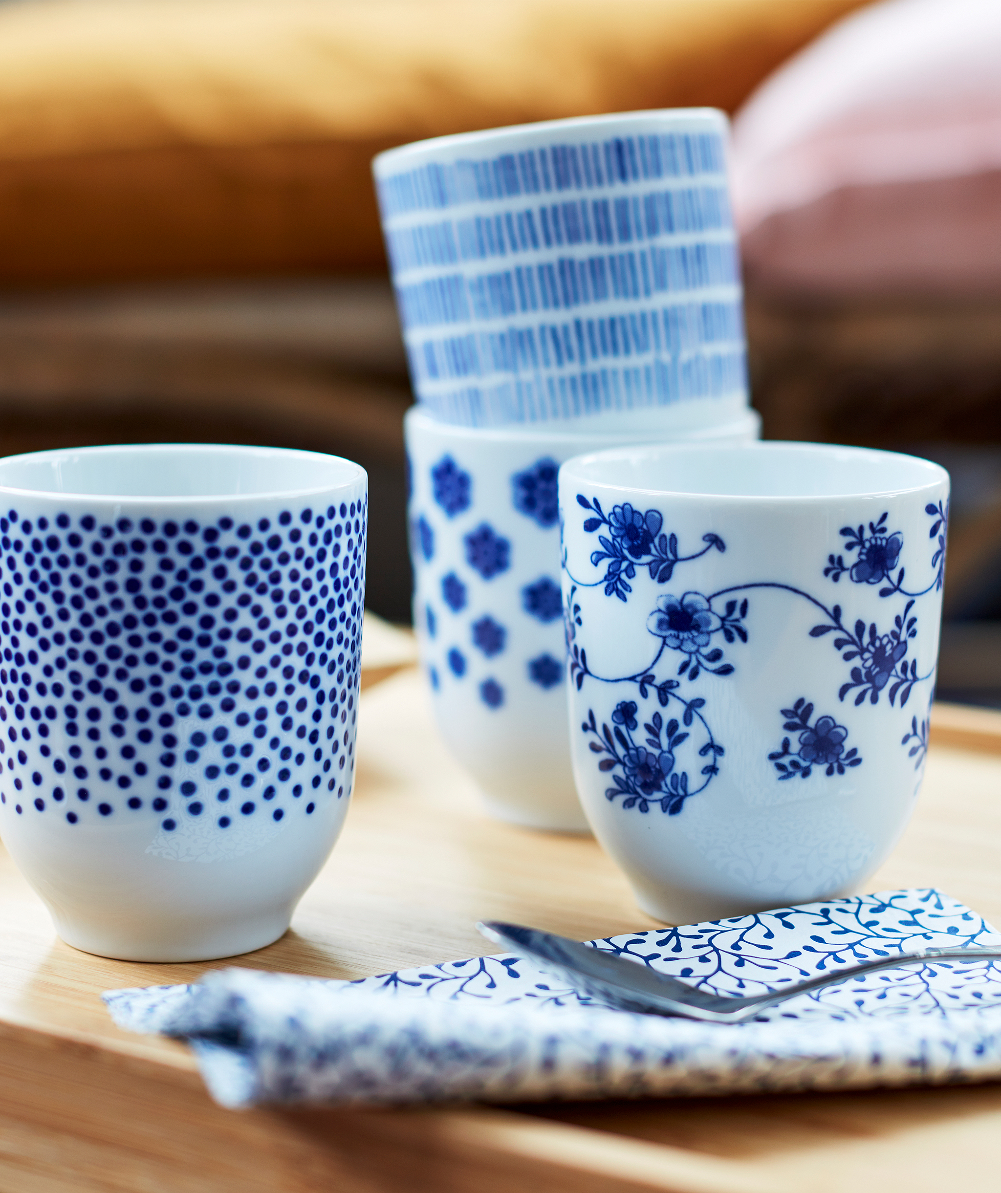 Four small tea mugs in white, decorated with different patterns in dark blue.