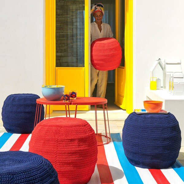 Outdoor summer scene, with table and OTTERÖN/INNERSKÄR pouffes with crocheted covers.