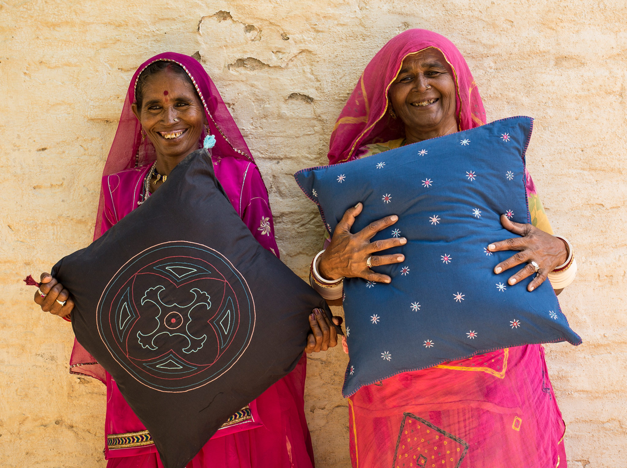 Picture showing two social entrepreneurs holding up their handcrafted pillows. They use business as a way to tackle social and environmental challenges, such as reducing poverty and empowering women.