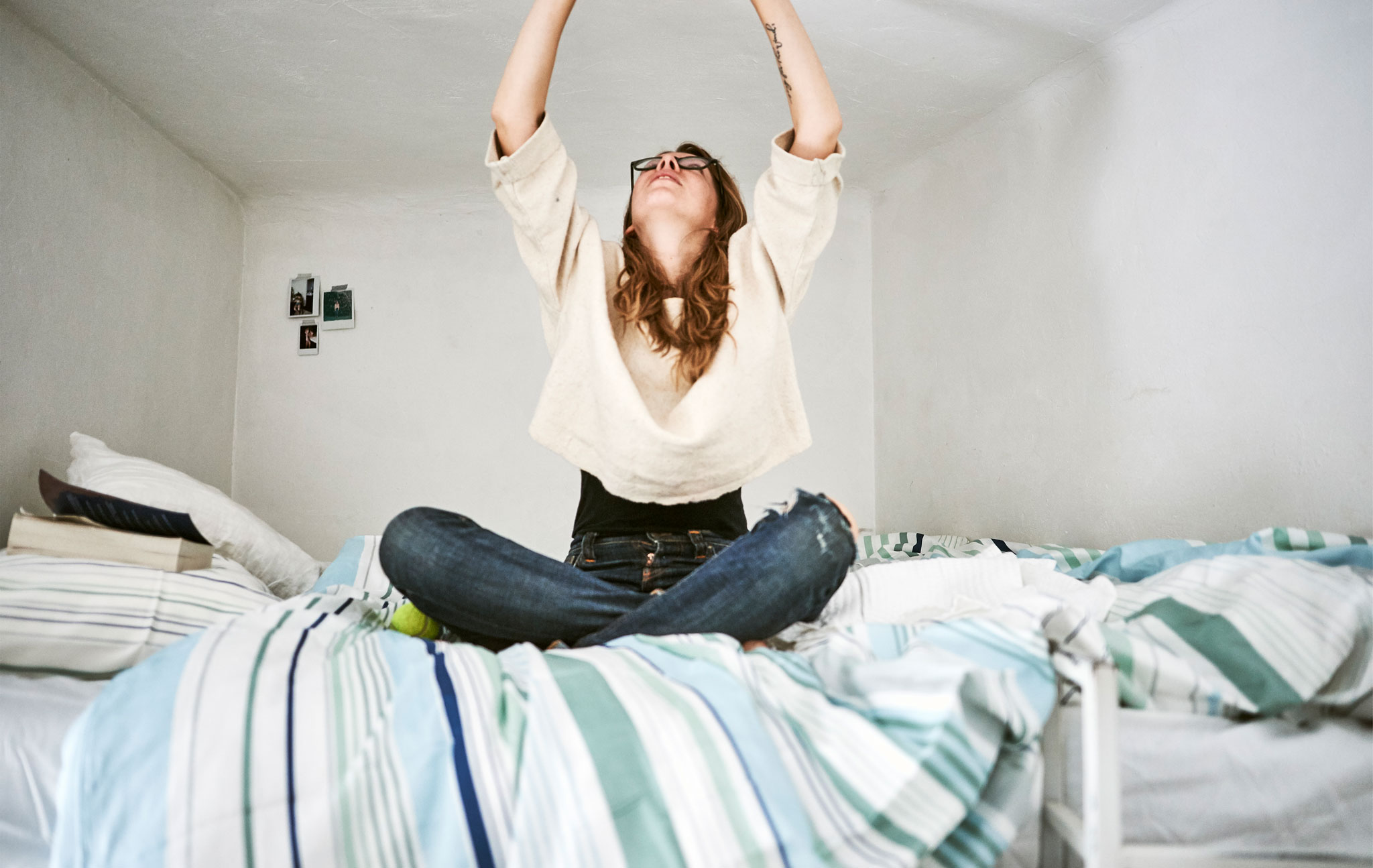 Rhianna reaching up to the ceiling on her mezzanine level bed.