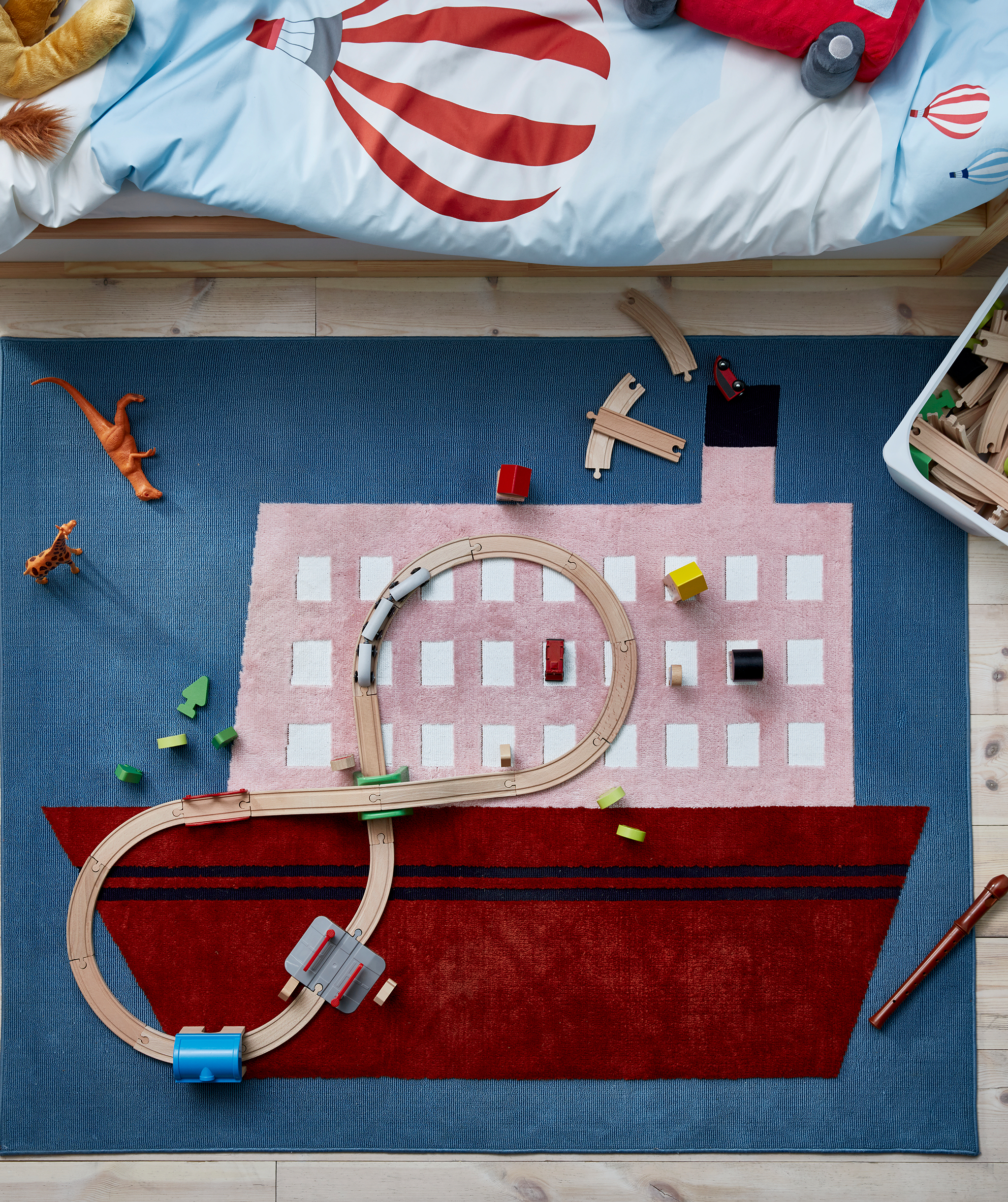 Rug with a boat motif, placed beneath a child’s bed, scattered with wooden railroad parts and other toys.