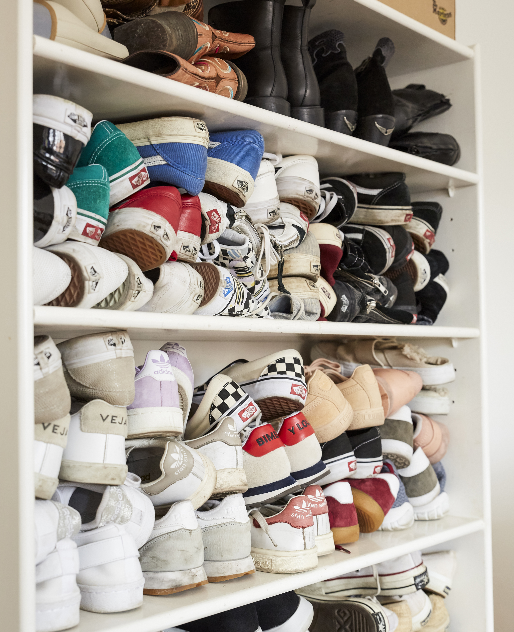 Shoes stacked on a bookcase.