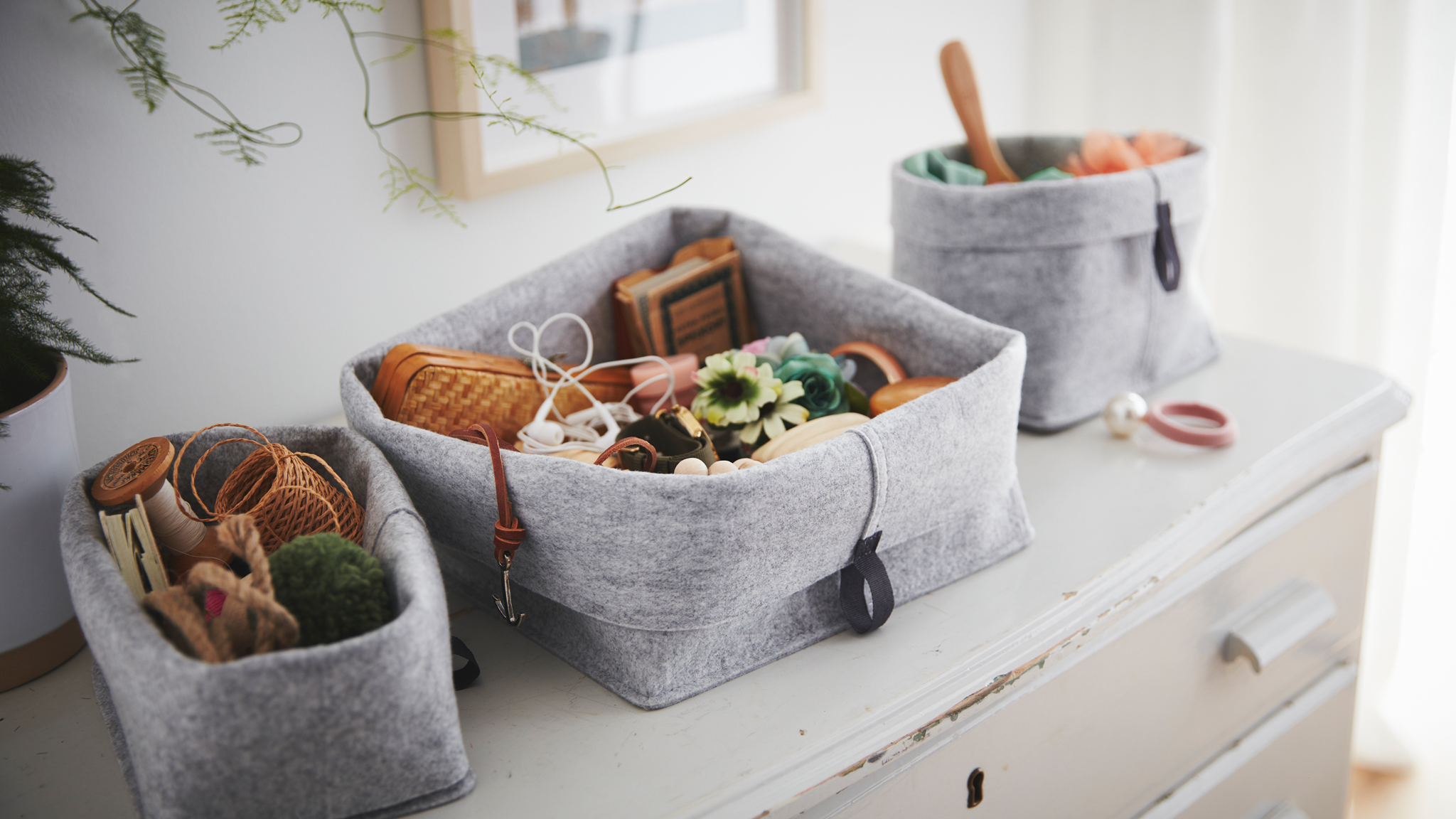 Standing on an old, worn chest of drawers are a set of RAGGISAR textile baskets, filled with trinkets and clutter.