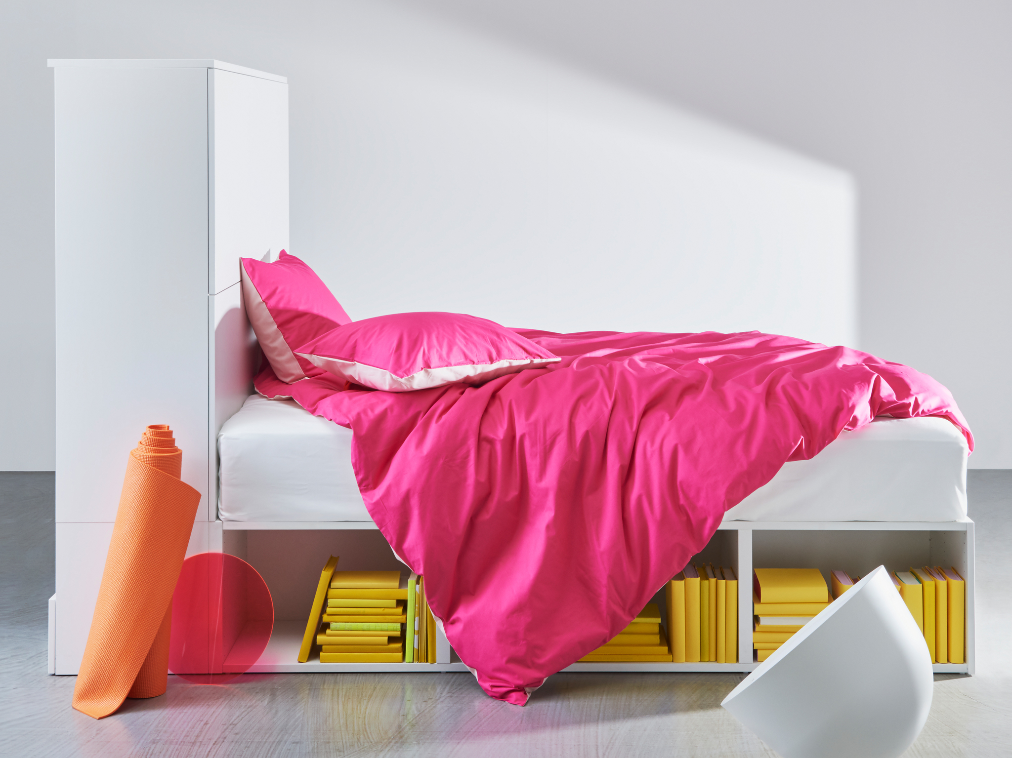 The white PLATSA bed frame with storage showing open shelves underneath the bed and closed storage with doors at one end.