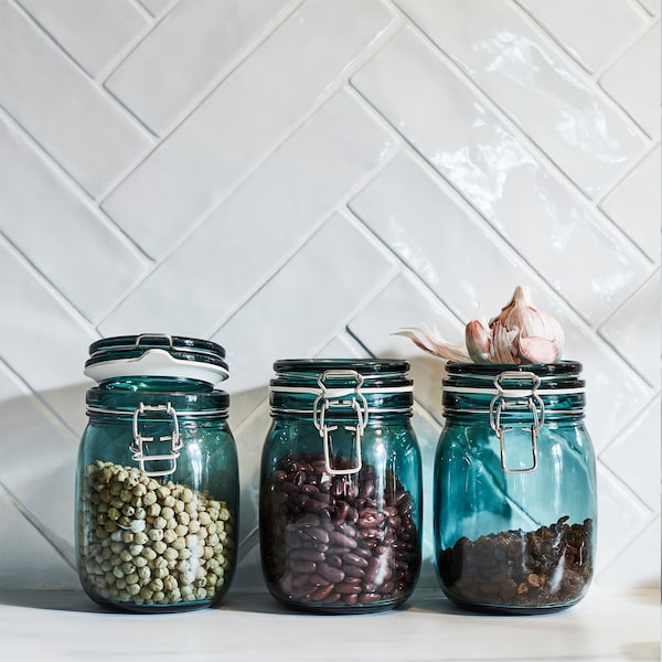 Three KORKEN jars in green see-through glass help preserve aromas and flavours. Dried raisins and beans are stored inside.