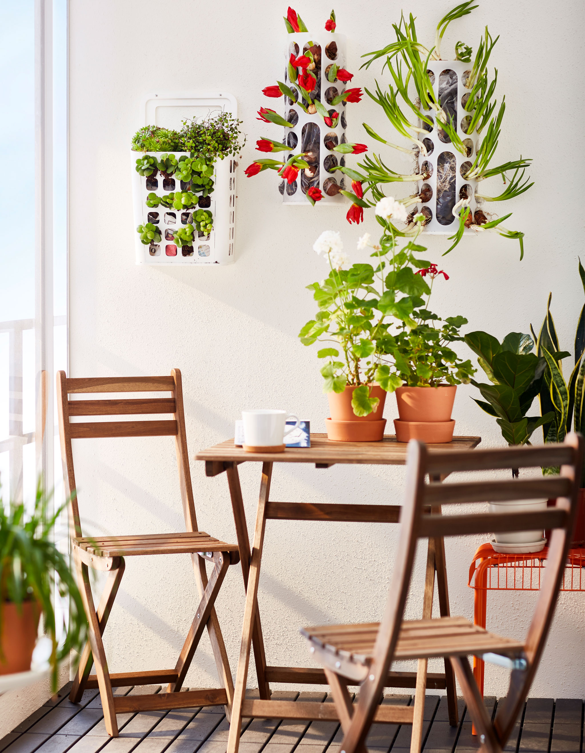 Three VARIERA plastic bag dispensers are hung on the wall of a balcony and used as planters.