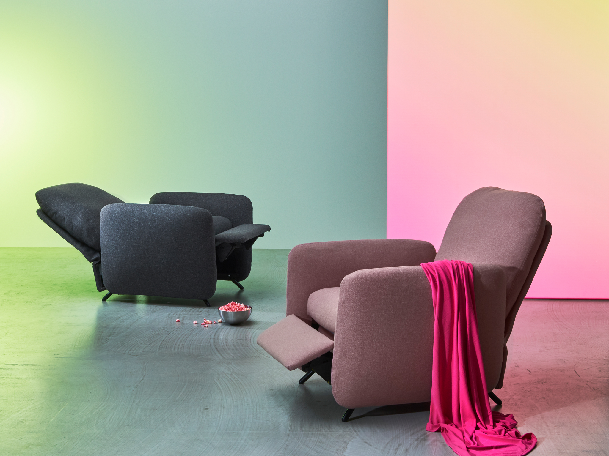 Two EKOLSUND recliners with an in-built footstool shown in grey and pink-brown in different reclining positions.